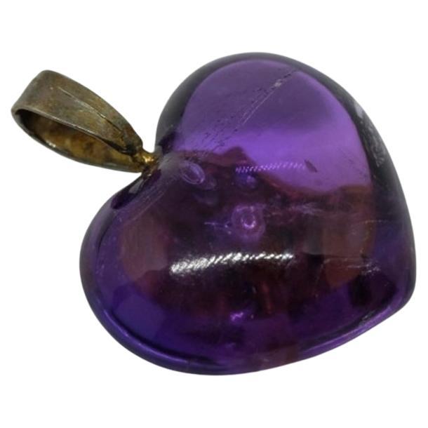 A beautiful heart-shaped purple pendant. Made out of amethyst and rose cut diamonds. In the middle of the heart there is a six-pointed star made of gold-toned metal and many little clear stones in it.