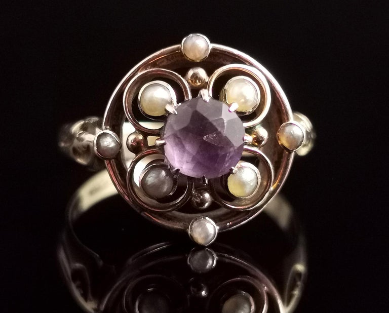 A pretty antique Amethyst and seed pearl ring in 18 karat yellow gold.

A conversion piece made from two pieces from the same era, the face is circular with scrolling wirework designs and set to the centre with a rich purple amethyst, surrounded by