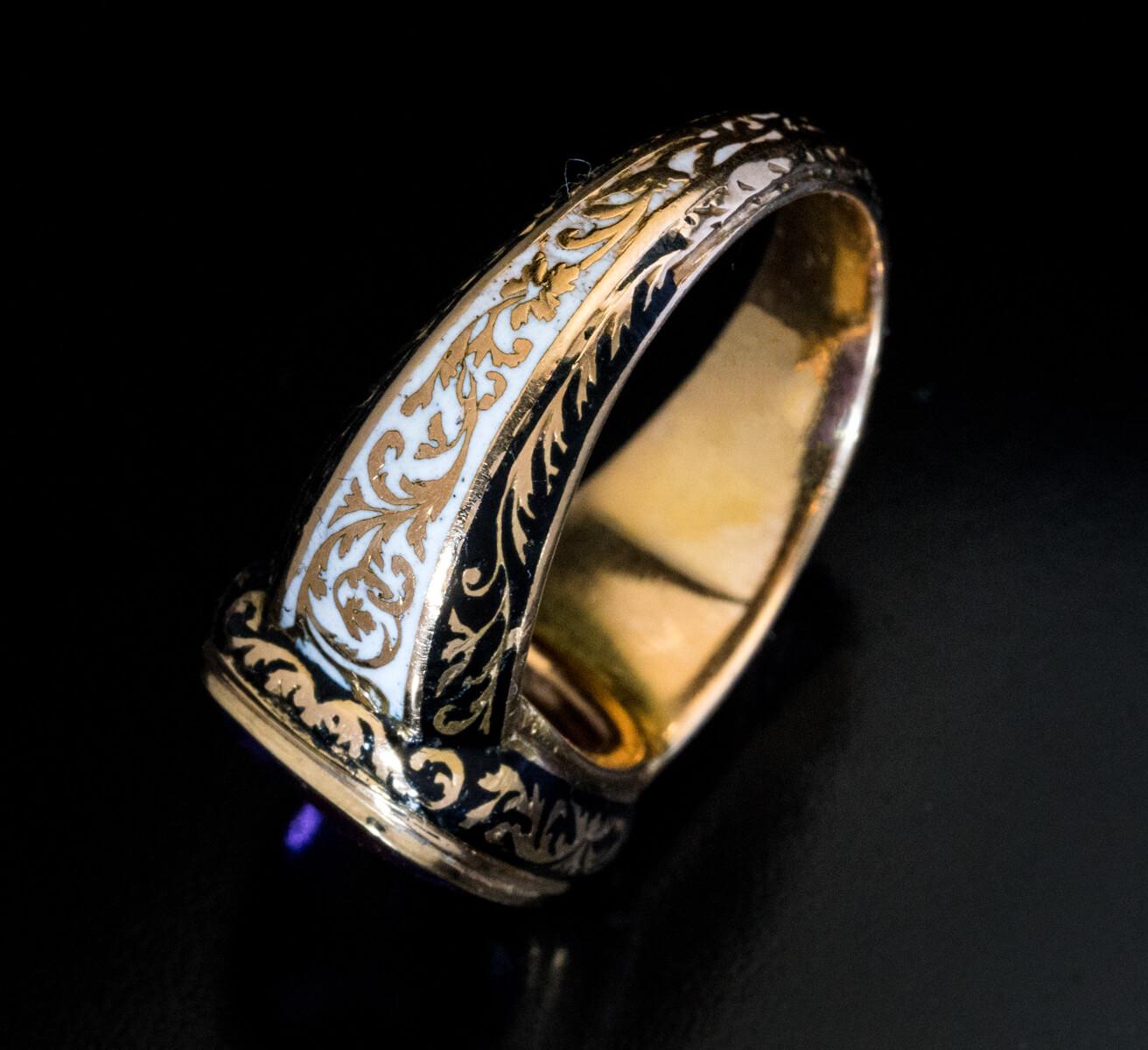 Circa 1830s

This late Georgian – early Victorian era heavy 18K gold ring features a very fine champleve enamel work in medieval / renaissance taste. The ring is bezel set with a cushion shape flat cut amethyst (13.3 x 10.7 x 5.8 mm) of a medium