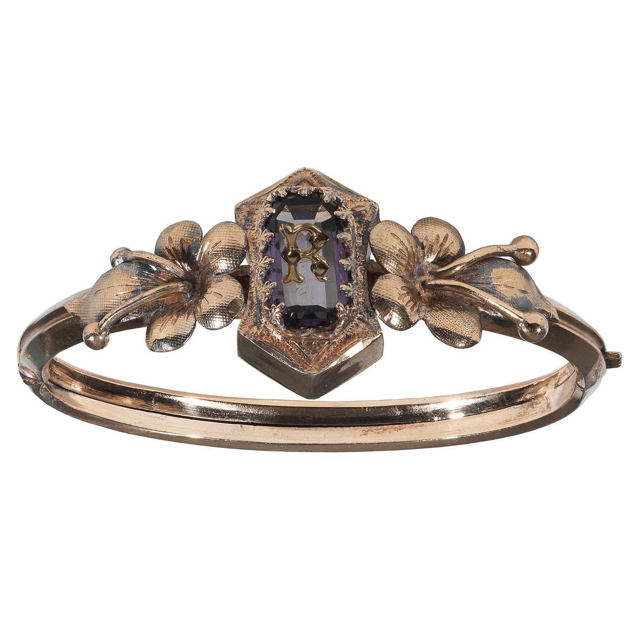 
Designed with a claw set amethyst engraved with a gold filled letter R to side floral decorations, the bangle is hinged and opens.  

Inner diameter: 60 mm