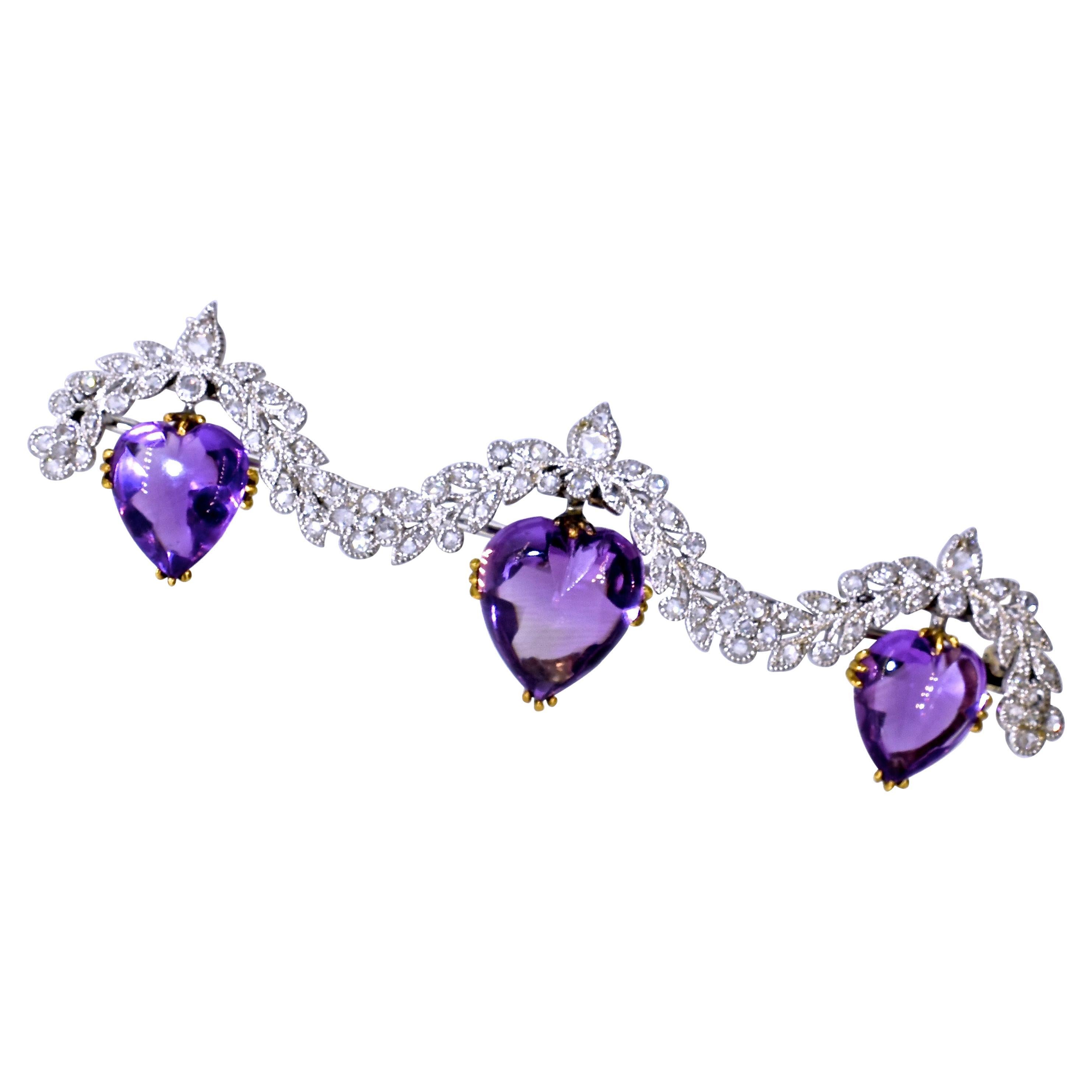 Antique heart shaped, buff-topped natural amethysts are suspended from a platinum and rose cut diamond garland.  The natural 3 amethysts are prong set in 18k yellow gold.  The platinum and diamond garland is well done exhibiting fine early 20th