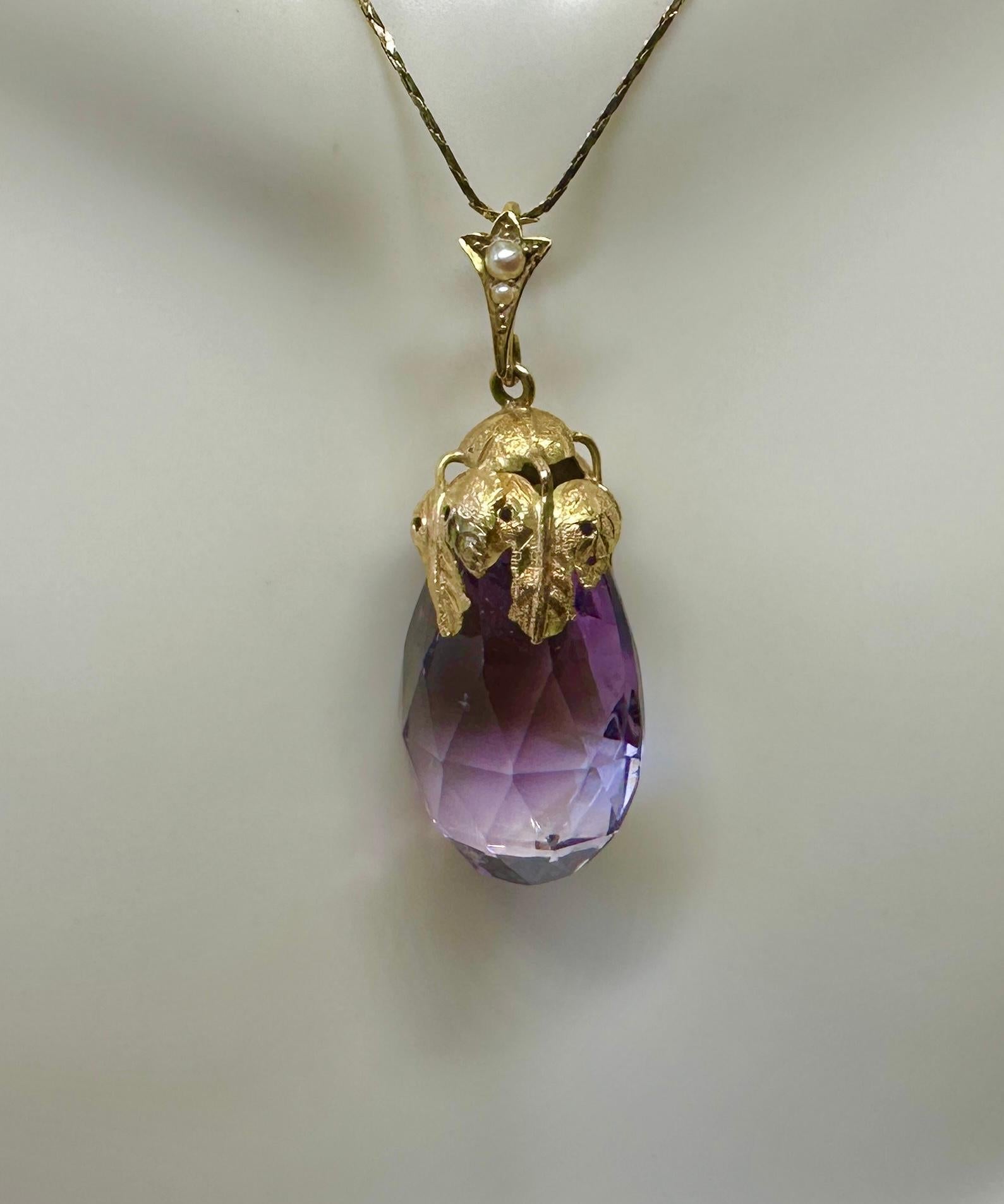 THIS IS A STUNNING ANTIQUE AMETHYST AND PEARL ETRUSCAN REVIVAL 14 KARAT GOLD PENDANT.
The exquisite pendant has a briolette faceted natural amethyst drop with a finely decorated Etruscan hand applied surmount with a leaf motif of extraordinary