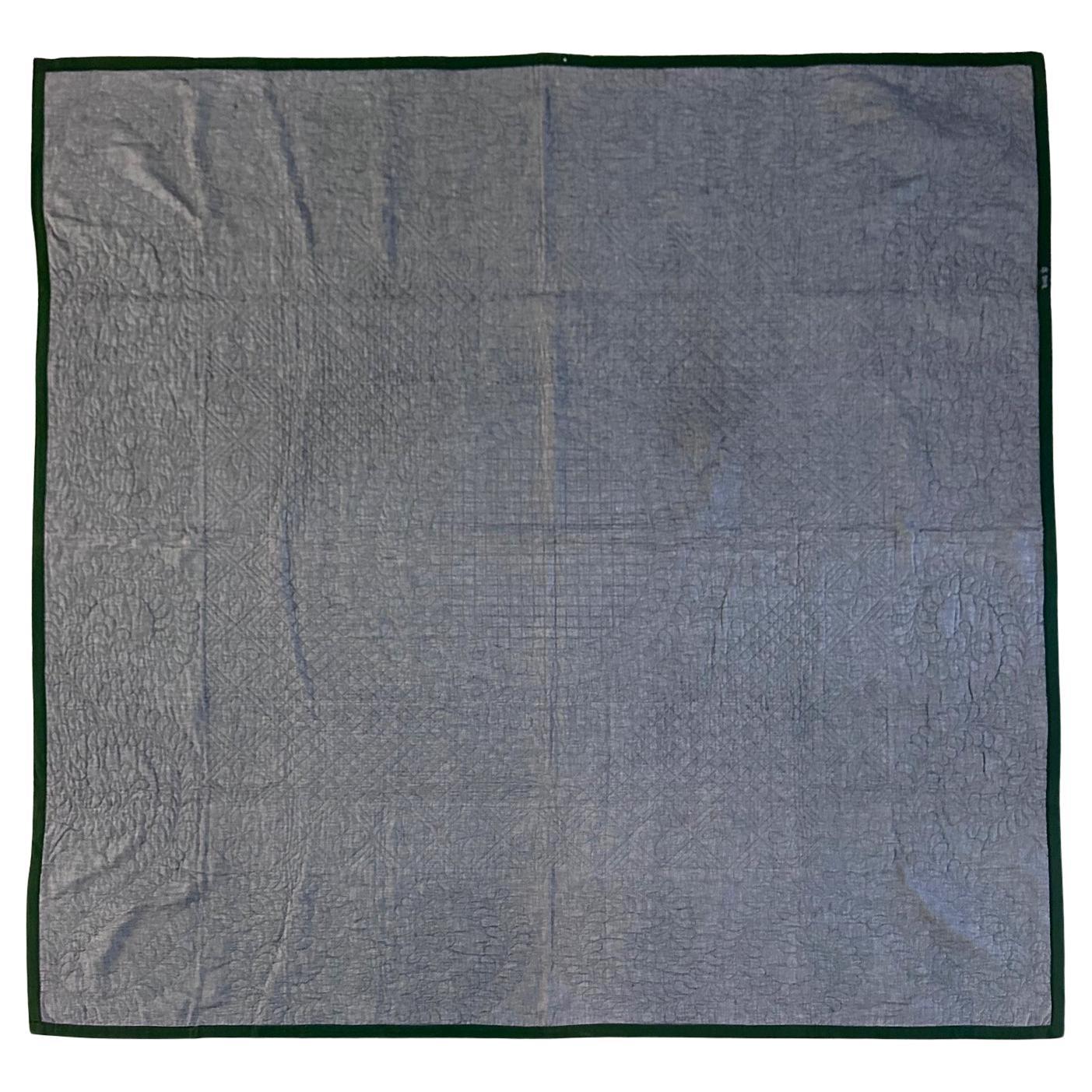 A large Amish quilt of center diamond pattern made from a red, green and light blue fine wool and cotton blend and backed by chambray cotton panel. The center diamond in the square pattern is supplemented with four smaller square corners, rendering