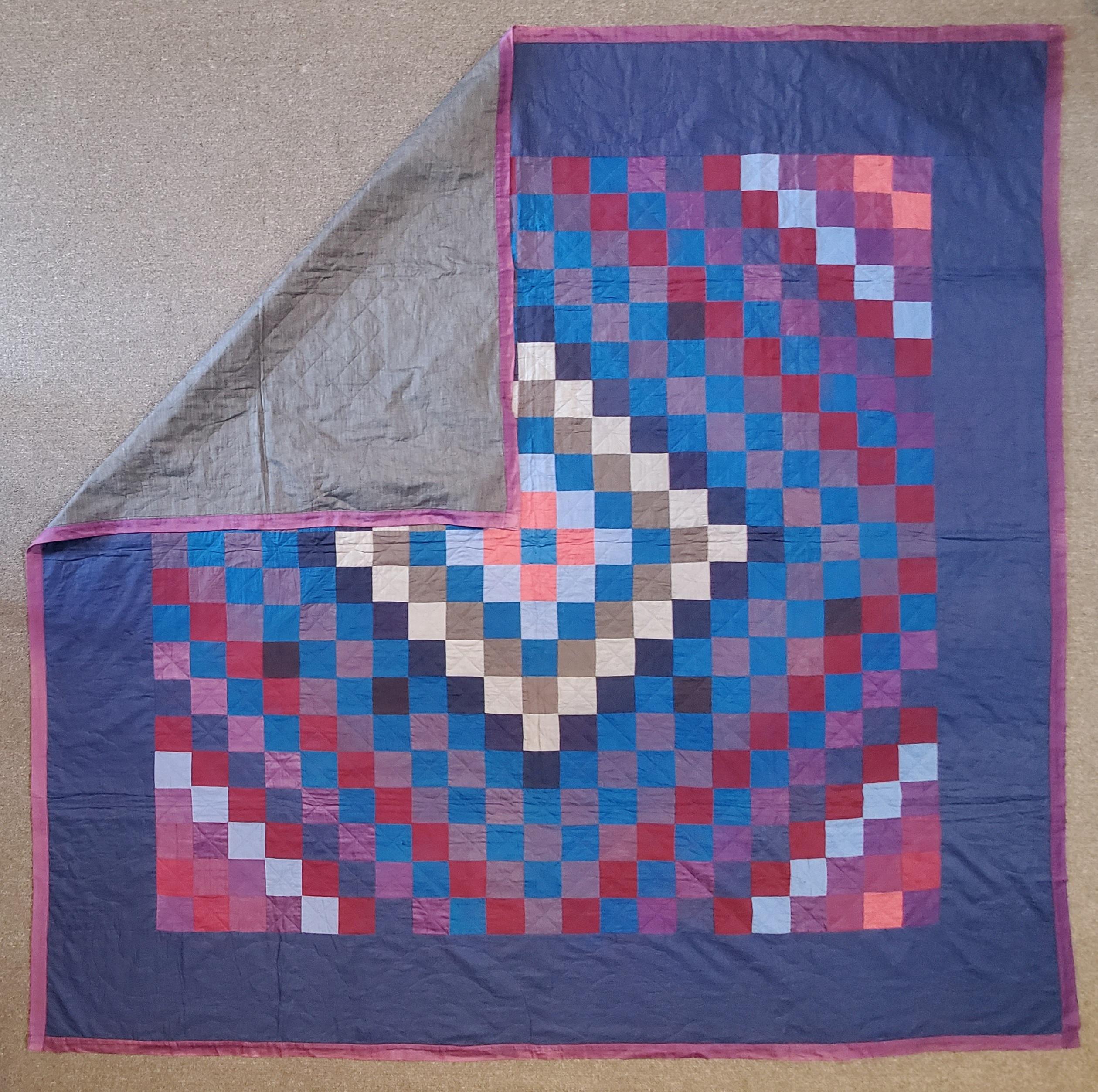 This Lancaster County, Pennsylvania Amish trip around the world pattern quilt is in fine condition. It is made from cotton and polished cotton blocks. The backing is in a polished cotton as well. The backing is in a grey shambrae polished cotton.
