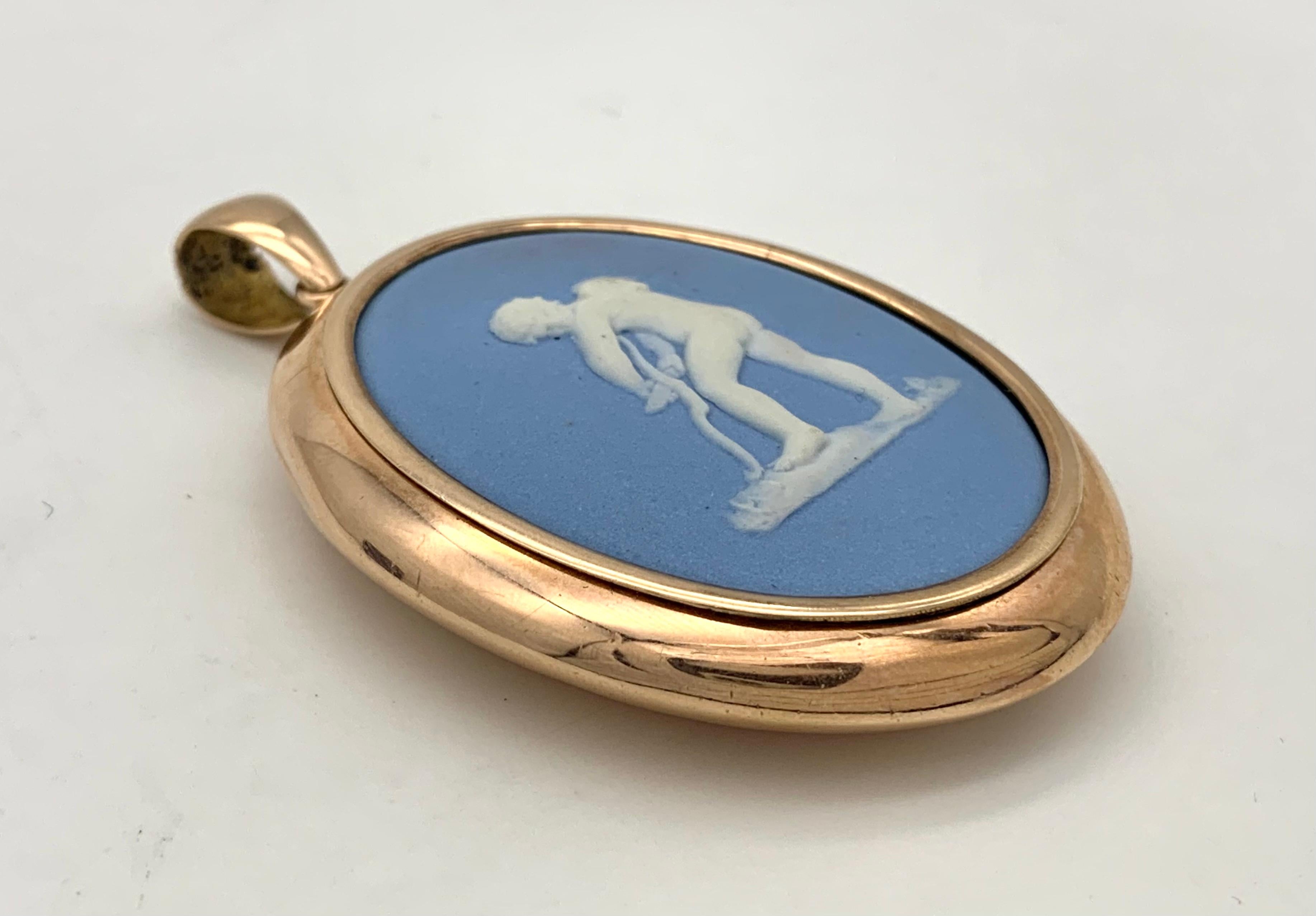 This fine size oval pendant is set with a pale blue Wedgwood cameo of cupid carving his bow and  looking over his shoulder.  The closed red gold setting is marked 9 karat.