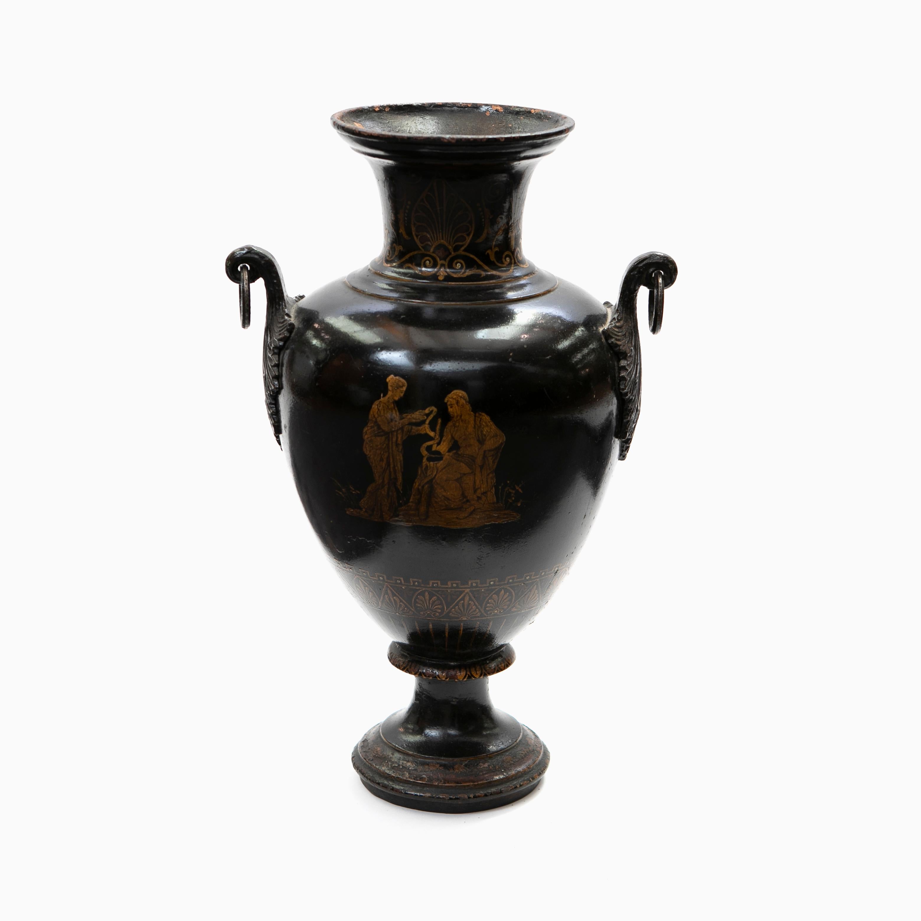 Dekorative Amphora mit Griffen im Stil der griechischen Klassik.
Die Vase ist aus schwarz lackiertem Gusseisen mit gelben Verzierungen, eine Seite zeigt eine klassische griechische Szene mit Paar.
Ursprünglicher Zustand.

Dänemark, um 1840.