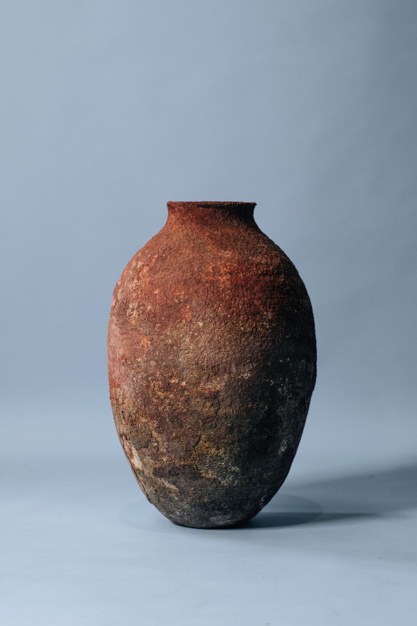 A beautifully weathered terracotta vessel from early 20th-century Anatolia, hand-thrown in coarse local clay and fired in a traditional wood kiln. Originally used for storing olive oil or grains, its narrow neck and rounded shoulders reflect a