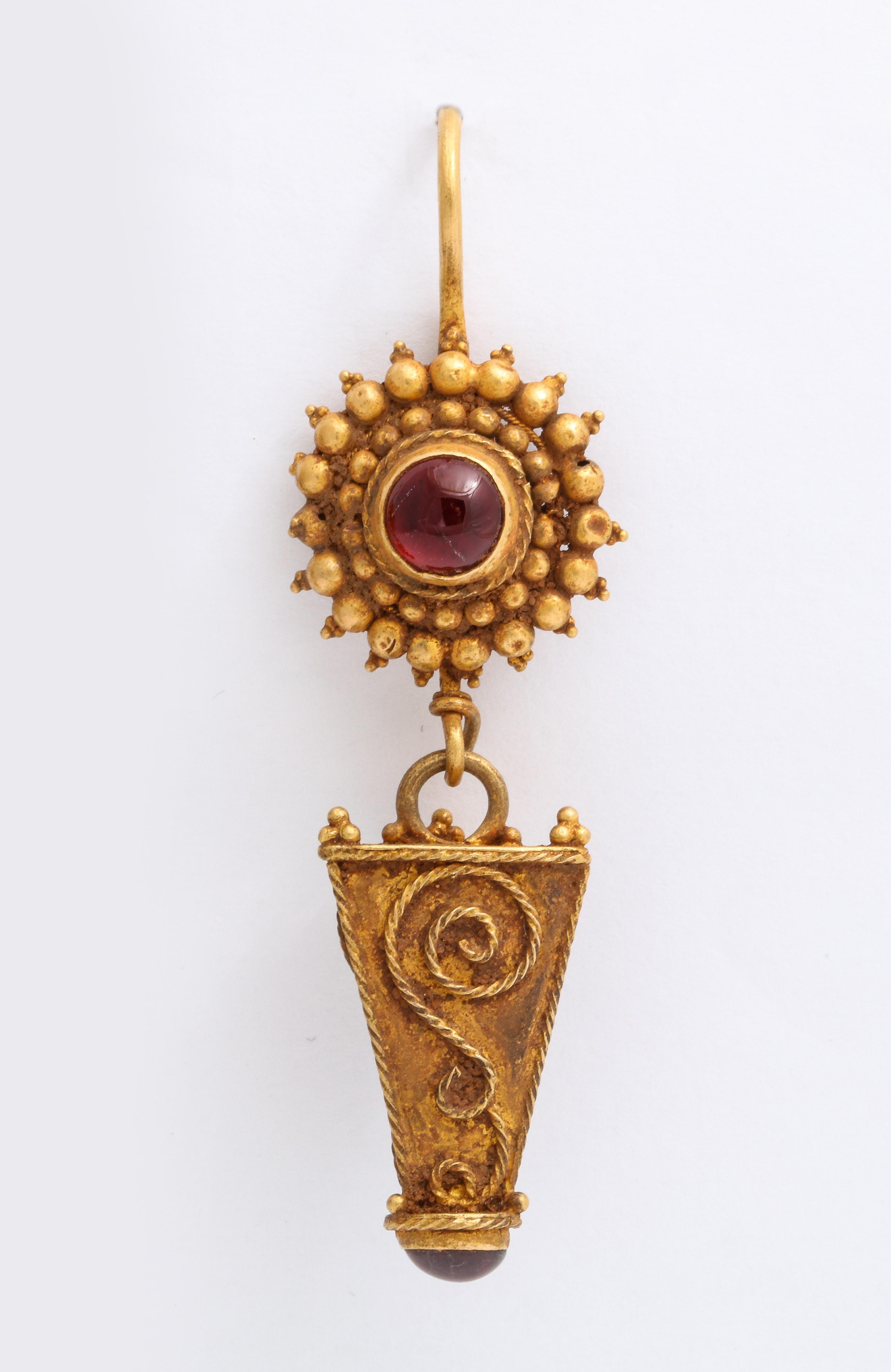 Fantastic late Roman gold earrings with intricate detail show suspension loops surrounded by rondels with concentric bauble decorations centered with a lovely red garnet. I am not being bombastic when I call these amazing. Long trapezoidal pendants