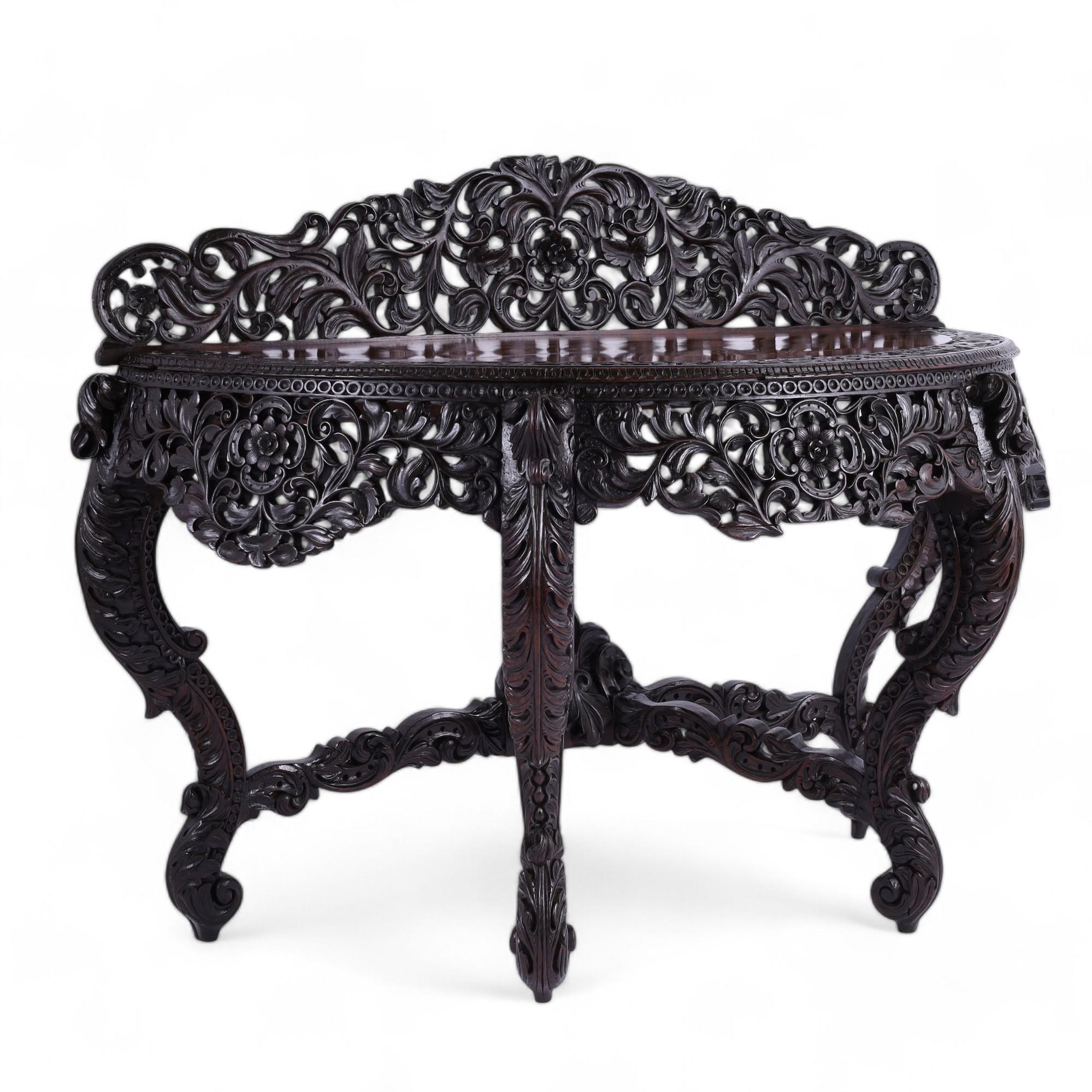 Wondrous 19th Century Anglo Indian console handcrafted in mahogany featuring elaborate flowing floral carvings on the gallery and skirt over four cabriole legs with carved acanthus leaves and four carved stretchers joined at a center leaf carving.