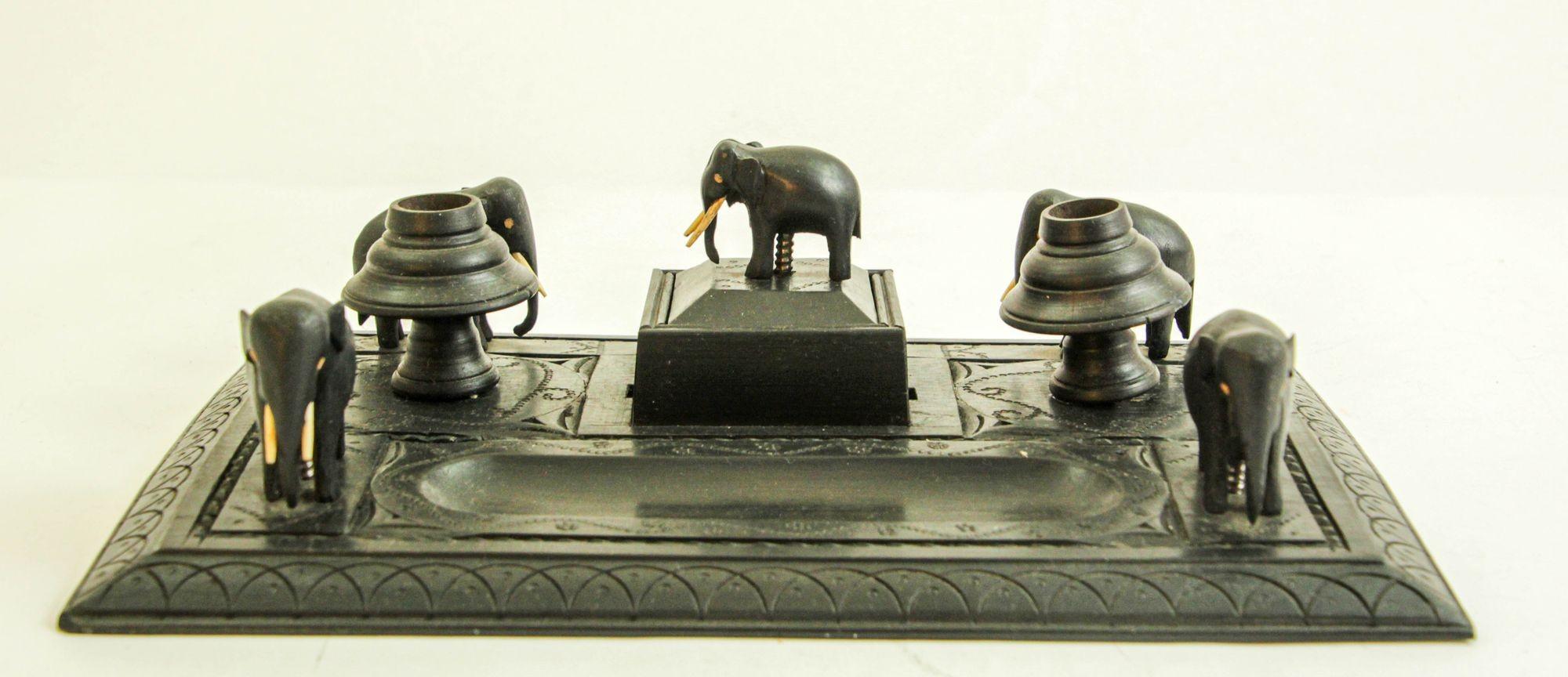 Antique Anglo-Indian Carved Ebony Figural Elephant Inkwell Desk Stand.
This is an antique Victorian colonial decorative desk ebony wood stand.
Late 19th century unusual design featuring five small intricately hand carved little elephants, 1 on each