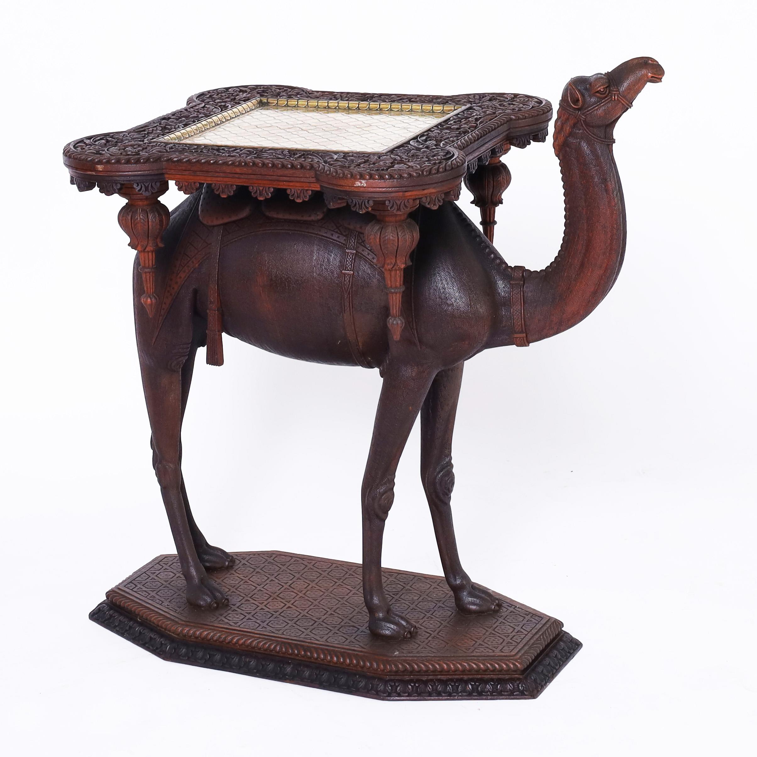 Enchanting 19th century Anglo Indian stand or table handcrafted in mahogany having an outlandish top with an inset brass tray and carved floral border on a carved camel with striking realism on a carved faux tile base. Best of the genre.
