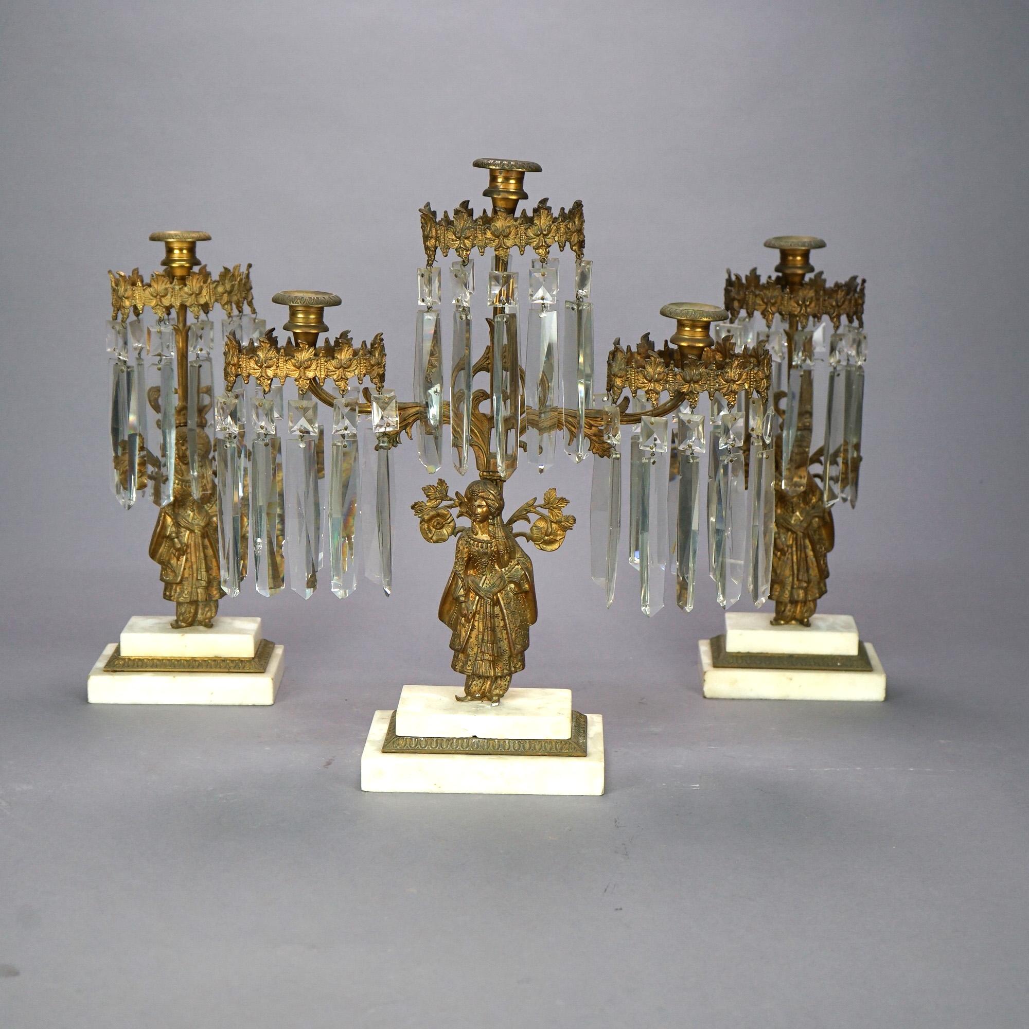 An antique girandole set offers cast brass construction with three elements, each with Anglo-Indian figures, marble bases and hanging cut crystals throughout, circa 1890

Measures: 1- 18.25''H x 10.5''W x 5''D''; 2- 15.5''H x 6.25''W x 4.25''D.