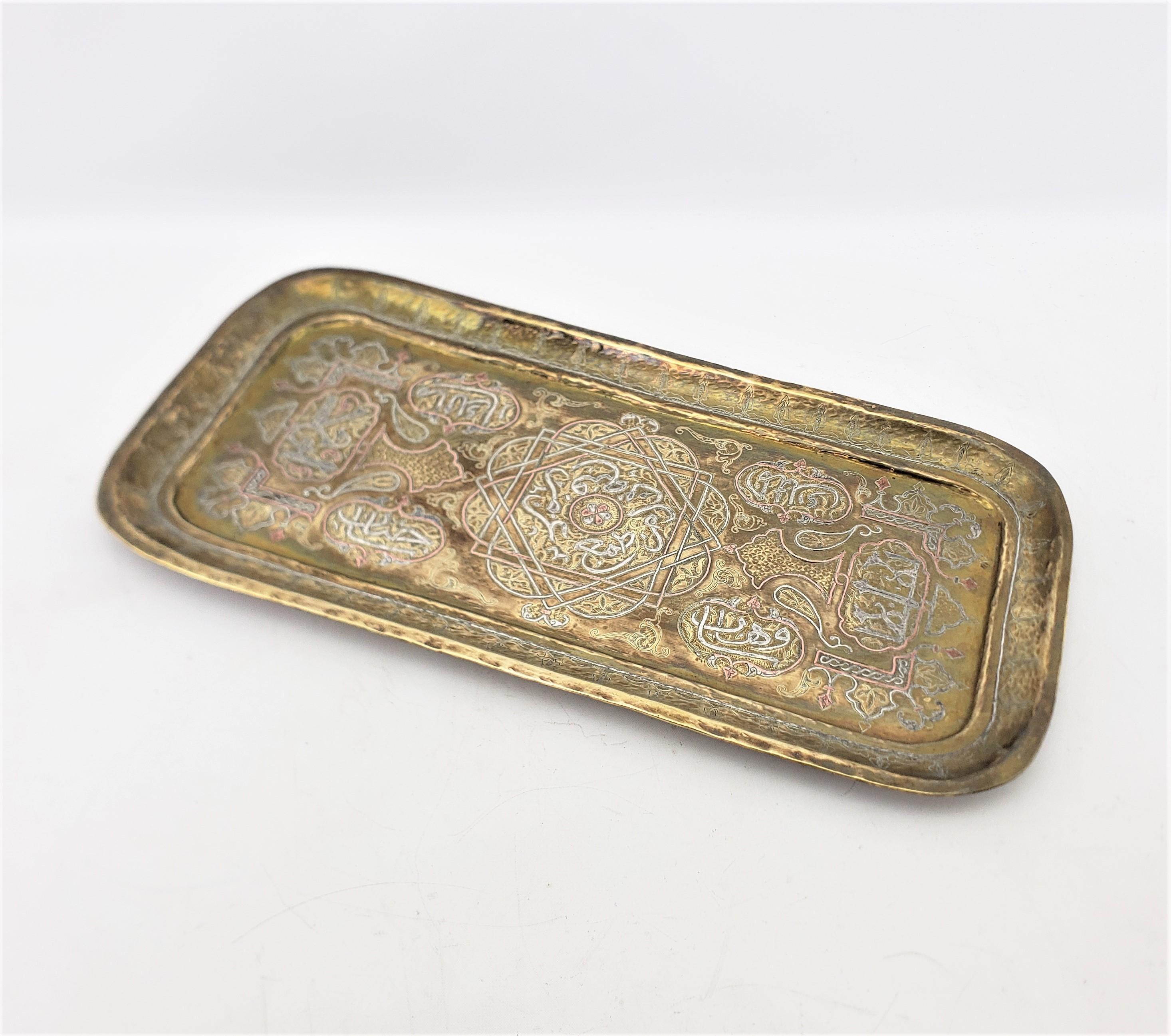 This antique serving tray is unsigned, but presumed to have originated from India and date to approximately 1920 and done in a period Anglo-Indian style. The tray is composed of brass which has been hand-hammered and ornately decorated with applied