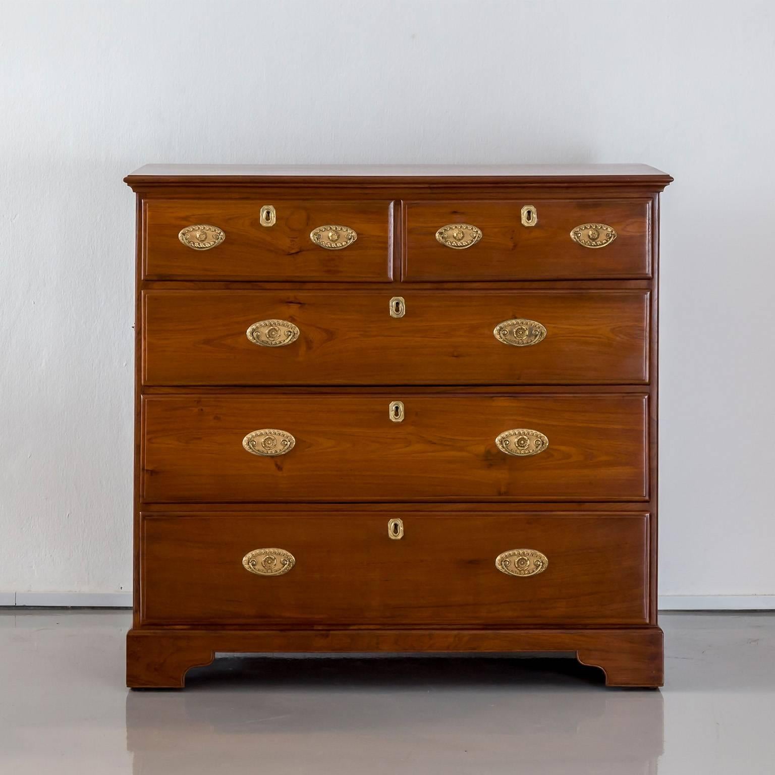 A British colonial Regency teakwood chest of drawers with a beautifully figured rectangular moulded top. Two short drawers above three long drawers of equal size, all with the original ring plate handles and escutcheons. The drawers with dovetail