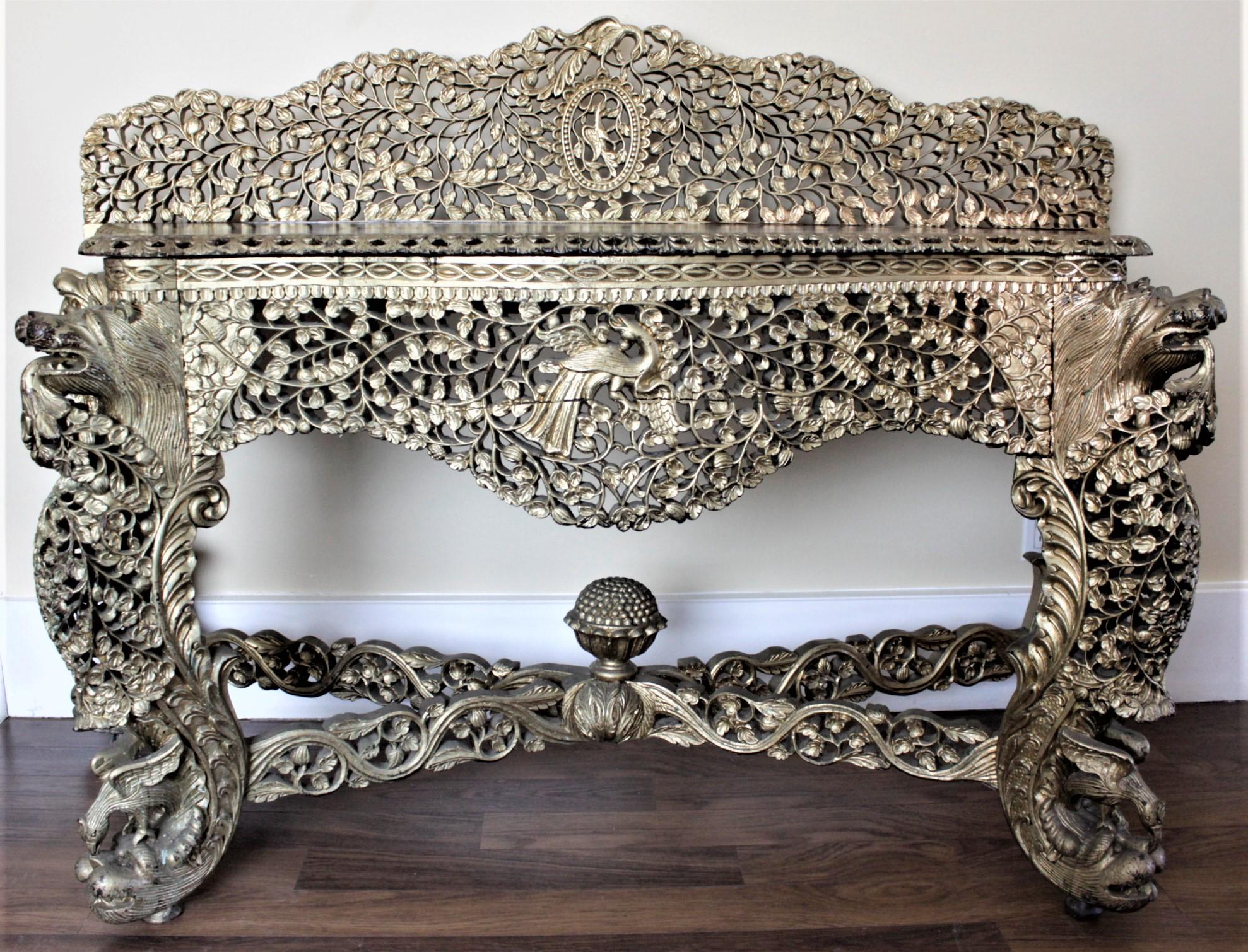 This antique and ornately hand-carved console table is unsigned, but presumed to have been made in India in approximately 1880 in the period Anglo-Indian style. This large and impressive console table has a serpentine shape with intricately carved