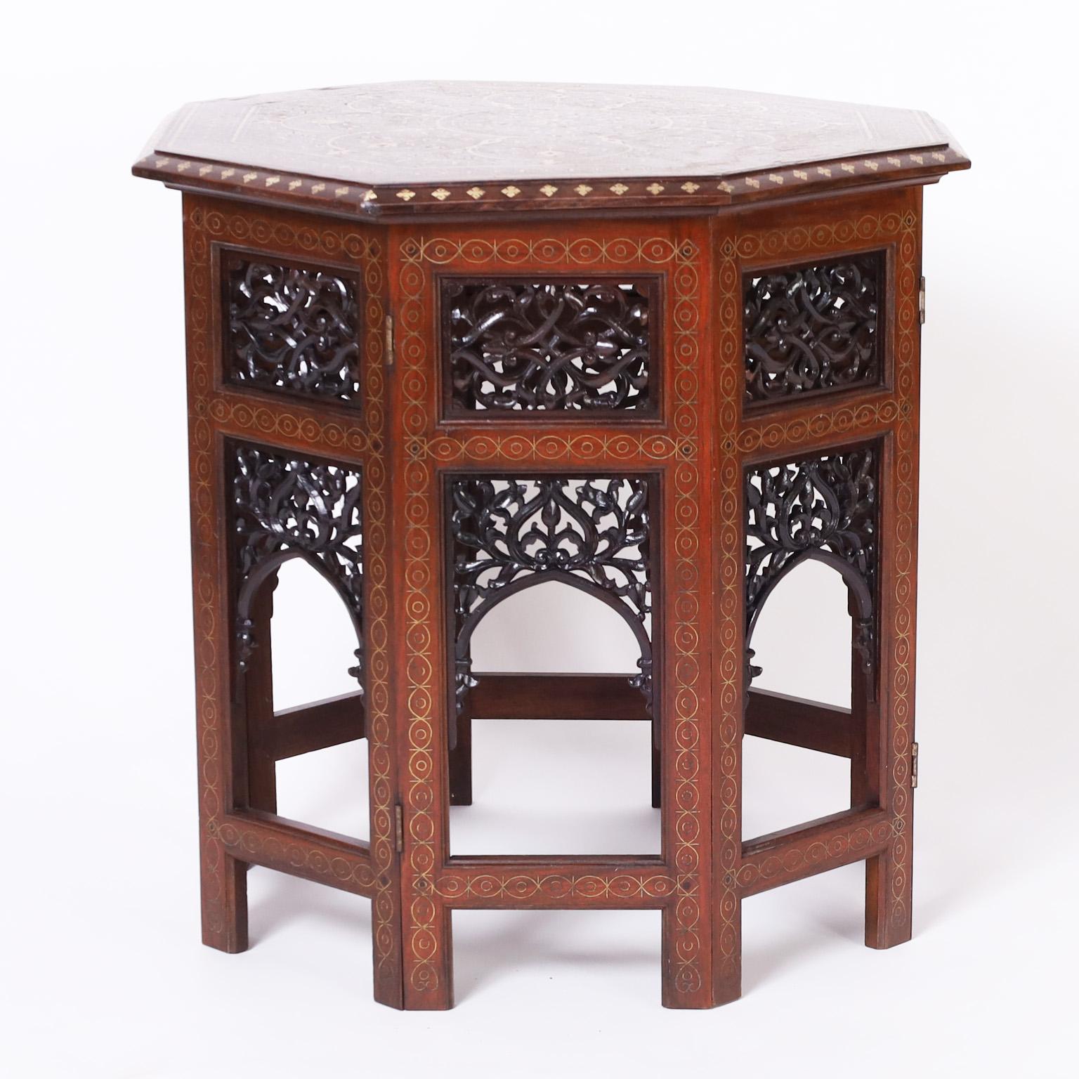 Impressive antique Anglo Indian stand or table with a rosewood octagon top having elaborate brass floral inlays over an eight sided mahogany base with carved and ebonized open fretwork. Complete with historical footnote 