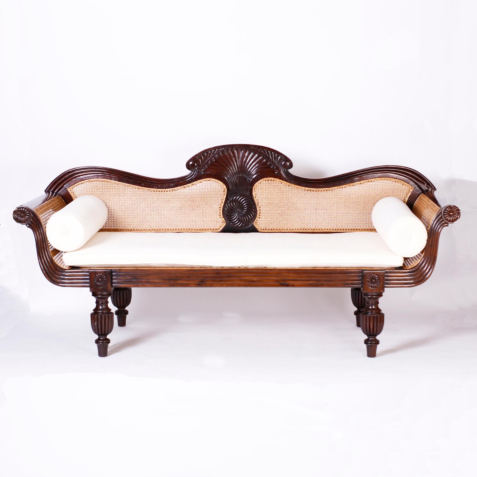 Antique British colonial Anglo Indian settee or sofa crafted in rosewood featuring a carved center back, caned seat, back and sides, beaded and carved front facade and turned and beaded classical legs.
