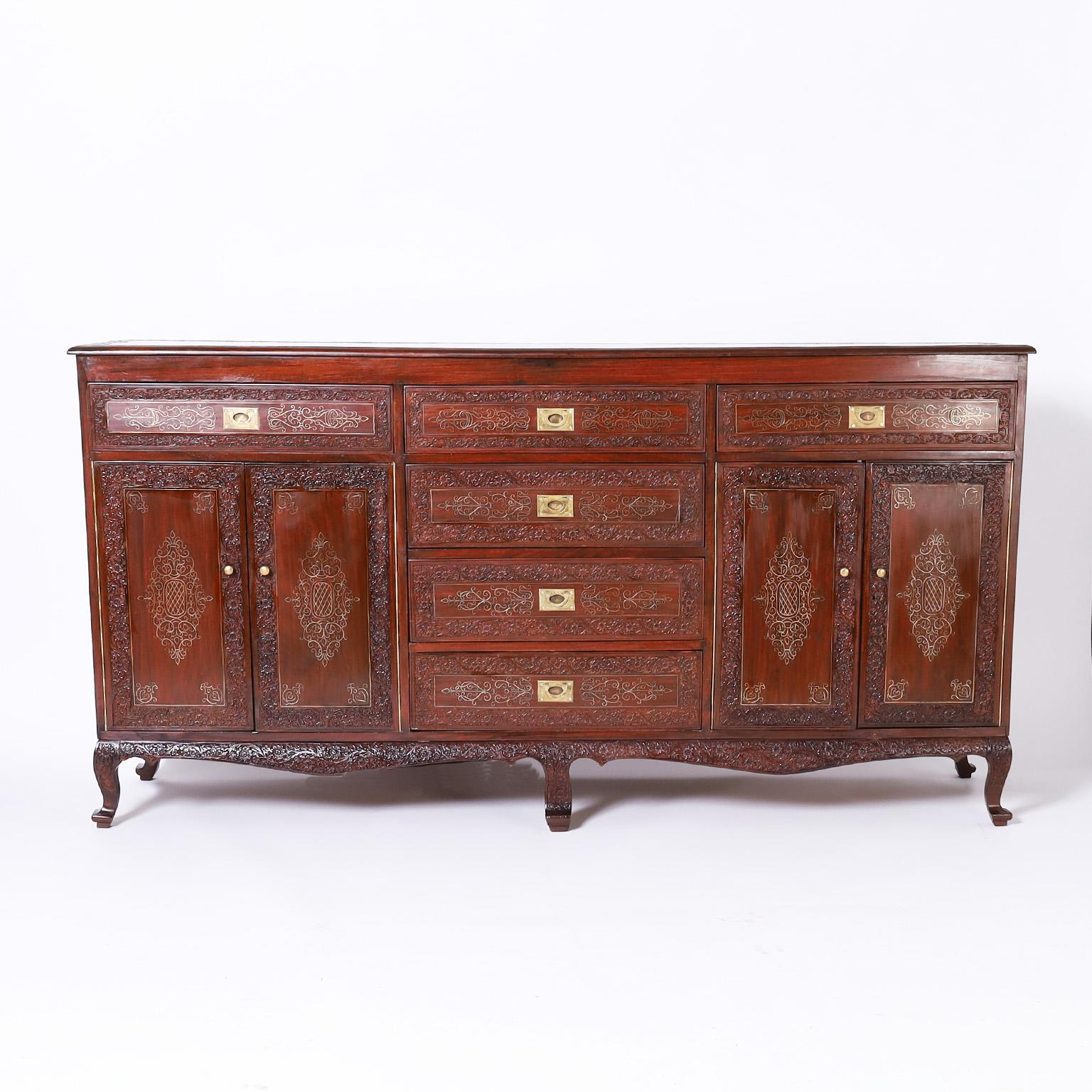 Opulent antique Anglo Indian sideboard or chest with six drawers and four doors crafted in grand scale with well grained rosewood with all the frill and frippery. Featuring ambitious floral carvings throughout, delicate floral brass string inlays on