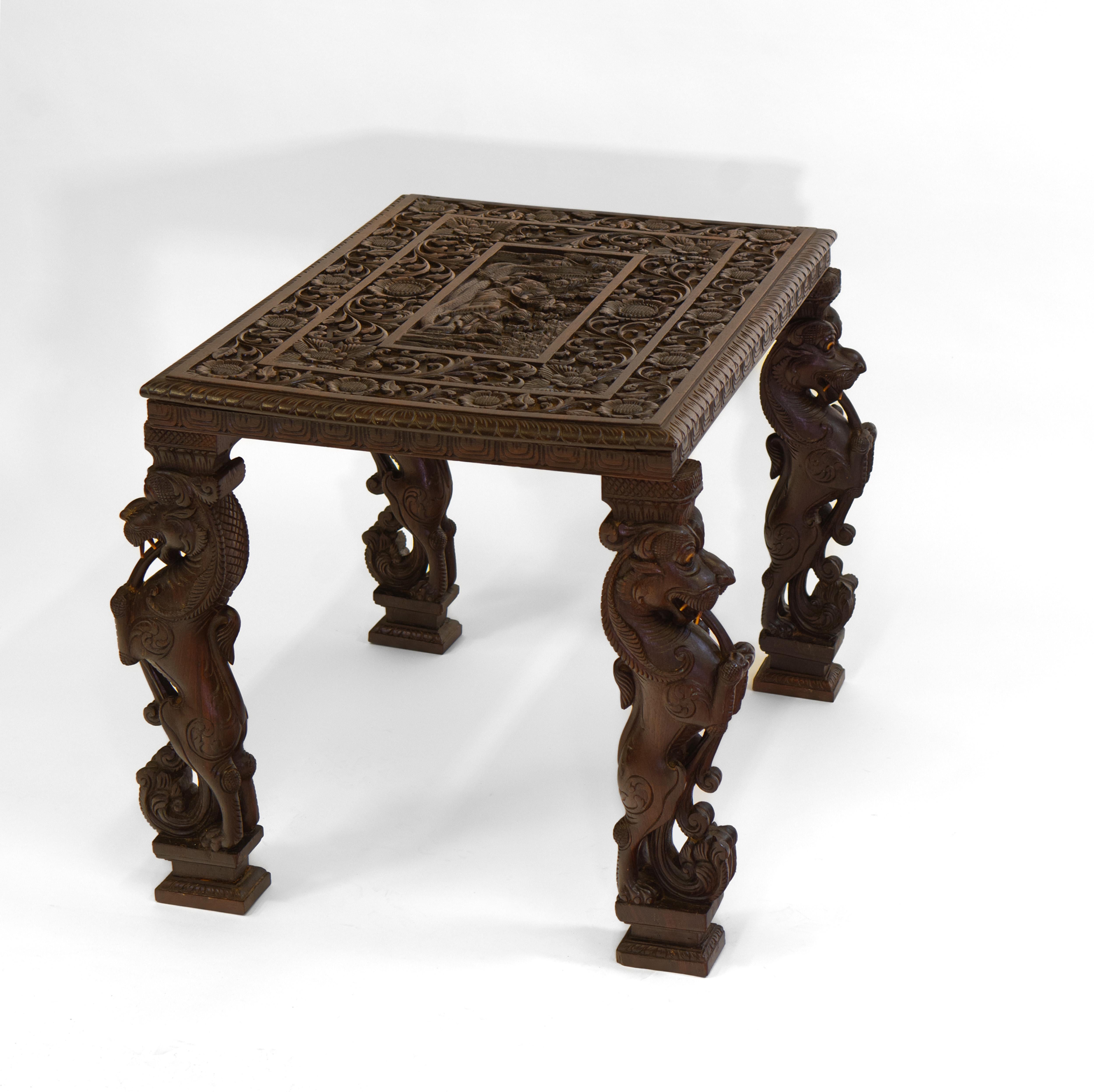 Magnifique table d'appoint anglo-indienne abondamment sculptée à la main avec des lions mythiques sur chaque pied. Elle est ornée d'une décoration florale complexe et d'un sommet sculpté représentant Vishnu. Circa 1900.

Livraison incluse au