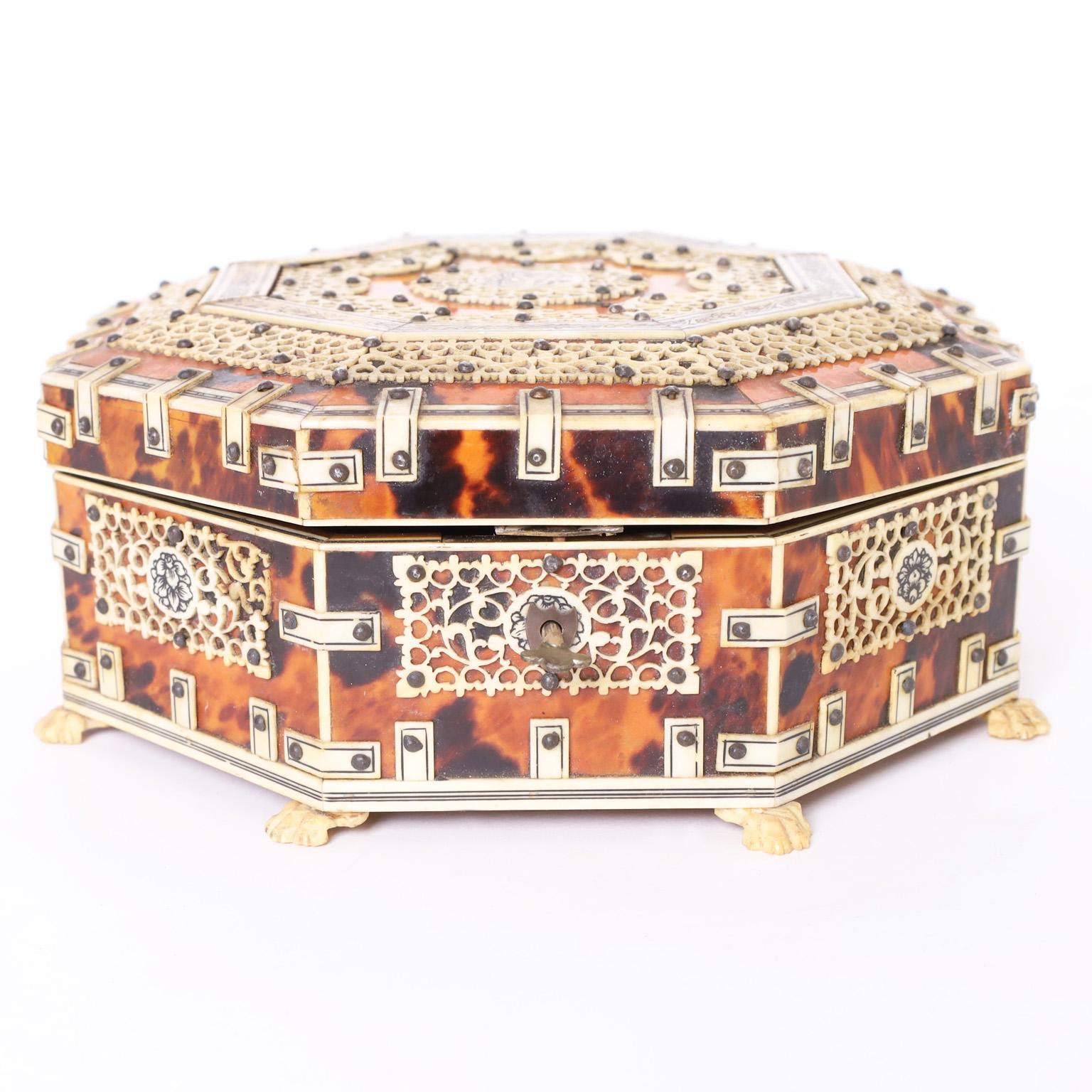 Lofty 19th century Anglo Indian octagon form lidded box handcrafted in wood clad in tortoise shell and ambitiously decorated with floral and geometric designs in bone with a center medallion of a tiger and eight cat paw feet. The inside in lined