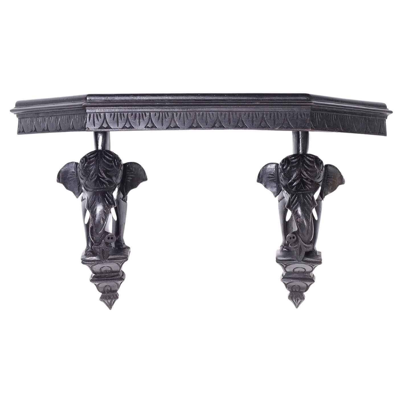 Intriguing British Colonial wall bracket or shelf carved from indigenous hardwood with an ebonized finish and featuring a pair of elephant supports on platforms.