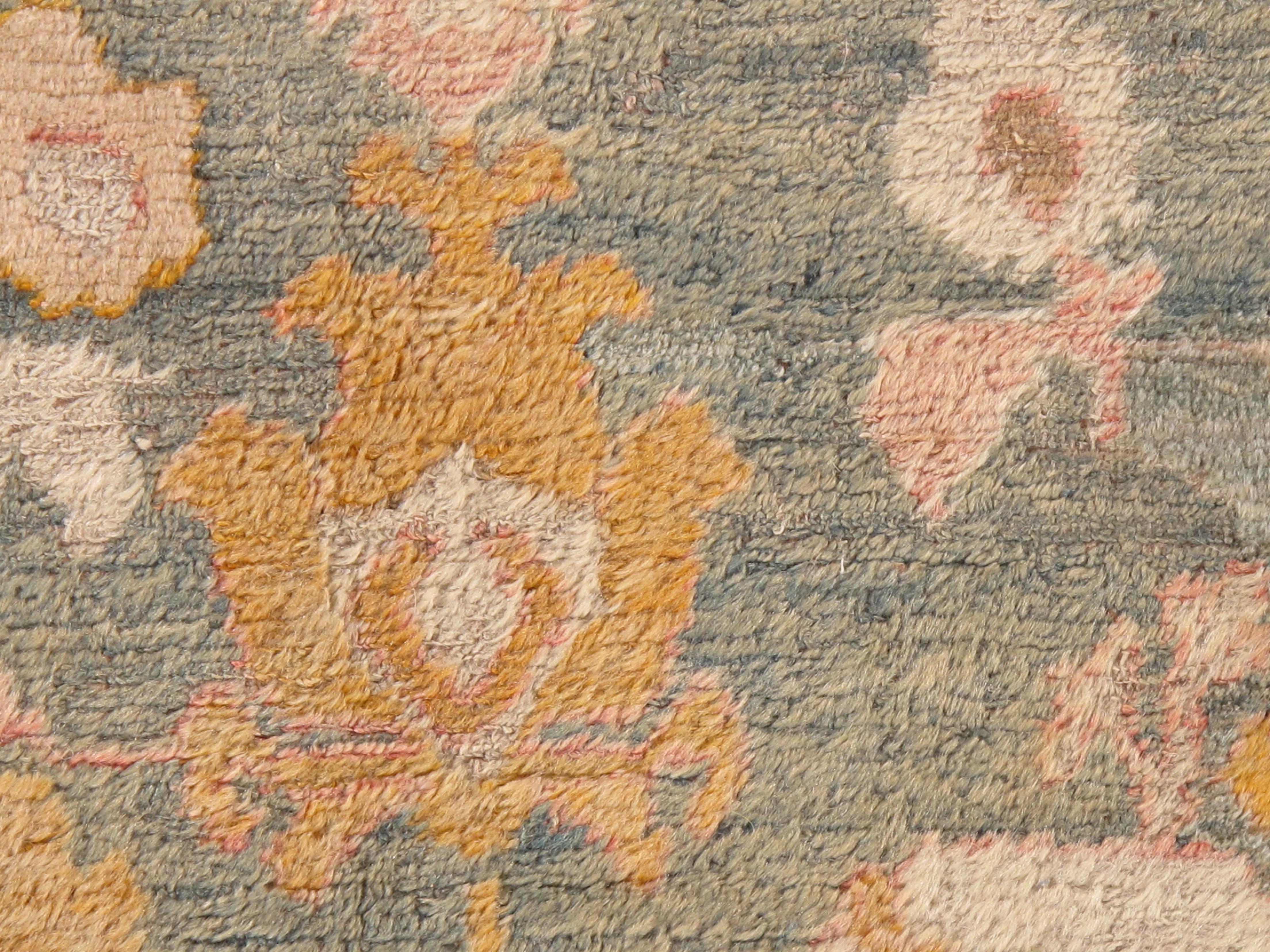 This exquisite late 19th century Angora Oushak carpet, dating from around 1880, showcases the artistry and craftsmanship of Turkish weaving traditions during the period. The carpet features a soft, serene light blue/green background, which