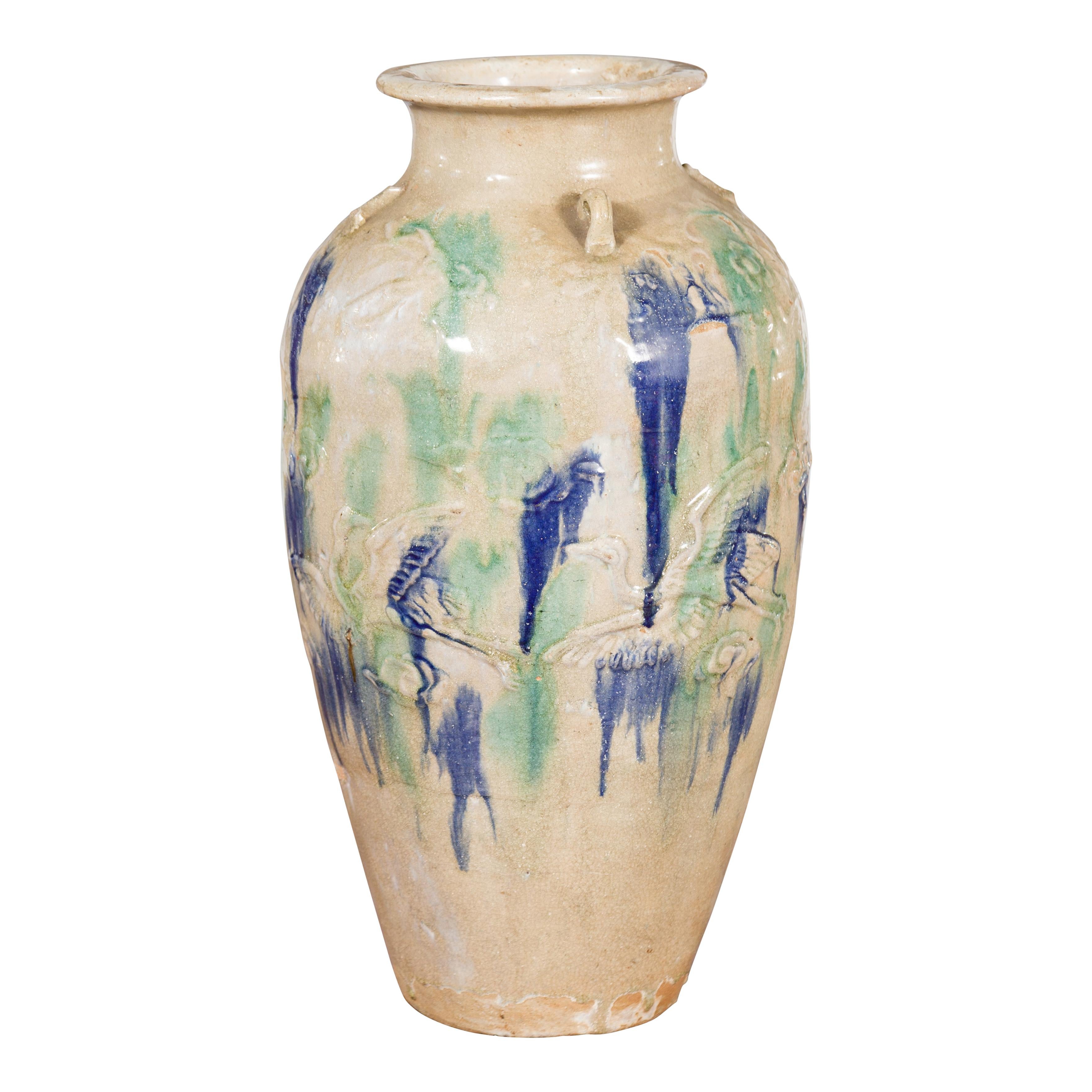 An antique Annamese ceramic storage vessel from the 19th century, with blue and green glaze and loop handles. Created during the 19th century, this large Annamese storage vessel features a cream toned tapering body adorned with green and blue glazed