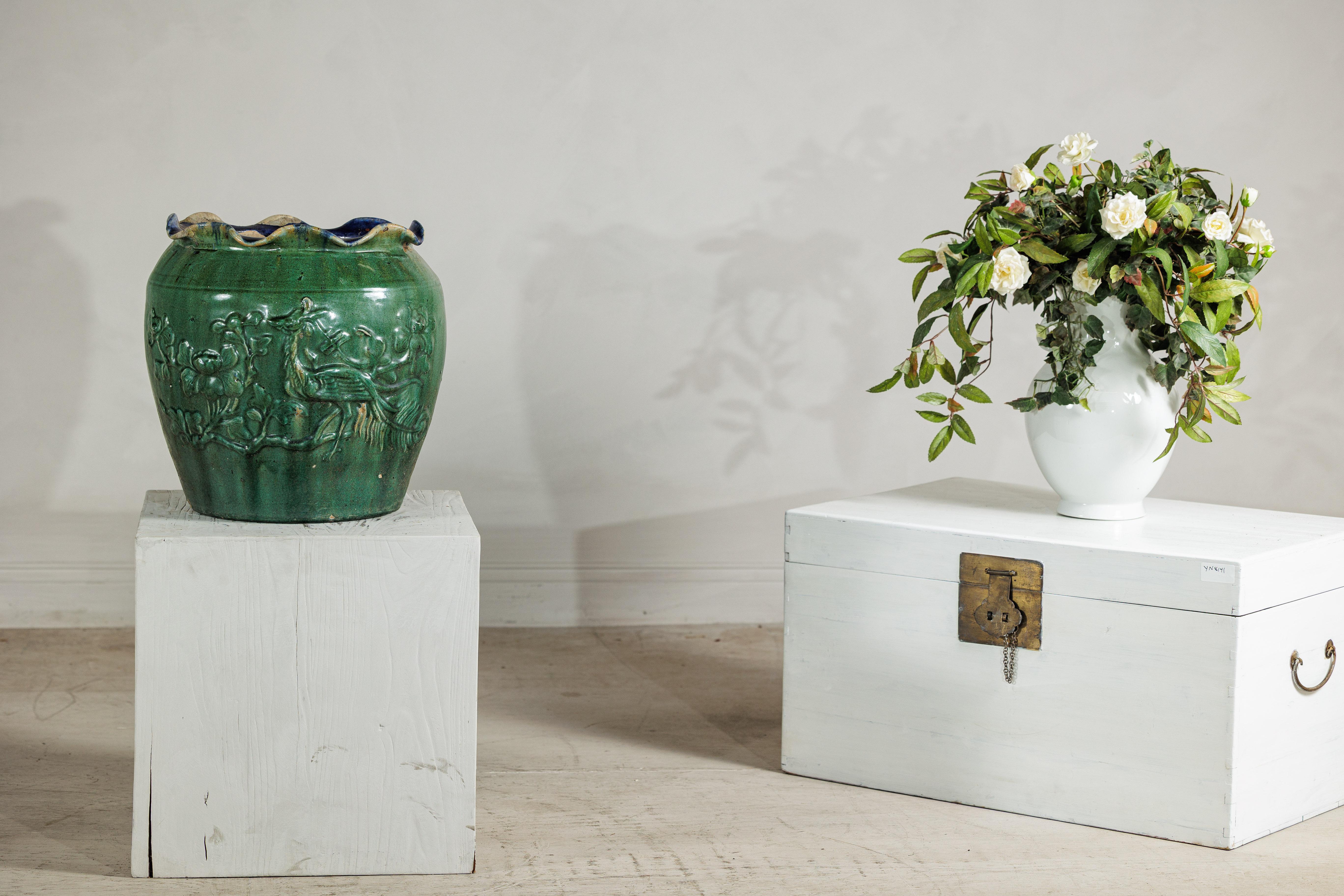 Un'antica fioriera vietnamita Annamese, che si distingue per il suo smalto verde brillante e per i dettagli scultorei della superficie. Il corpo arrotondato del vaso è riccamente decorato in rilievo con uccelli fenice tra rami fioriti, simboli di