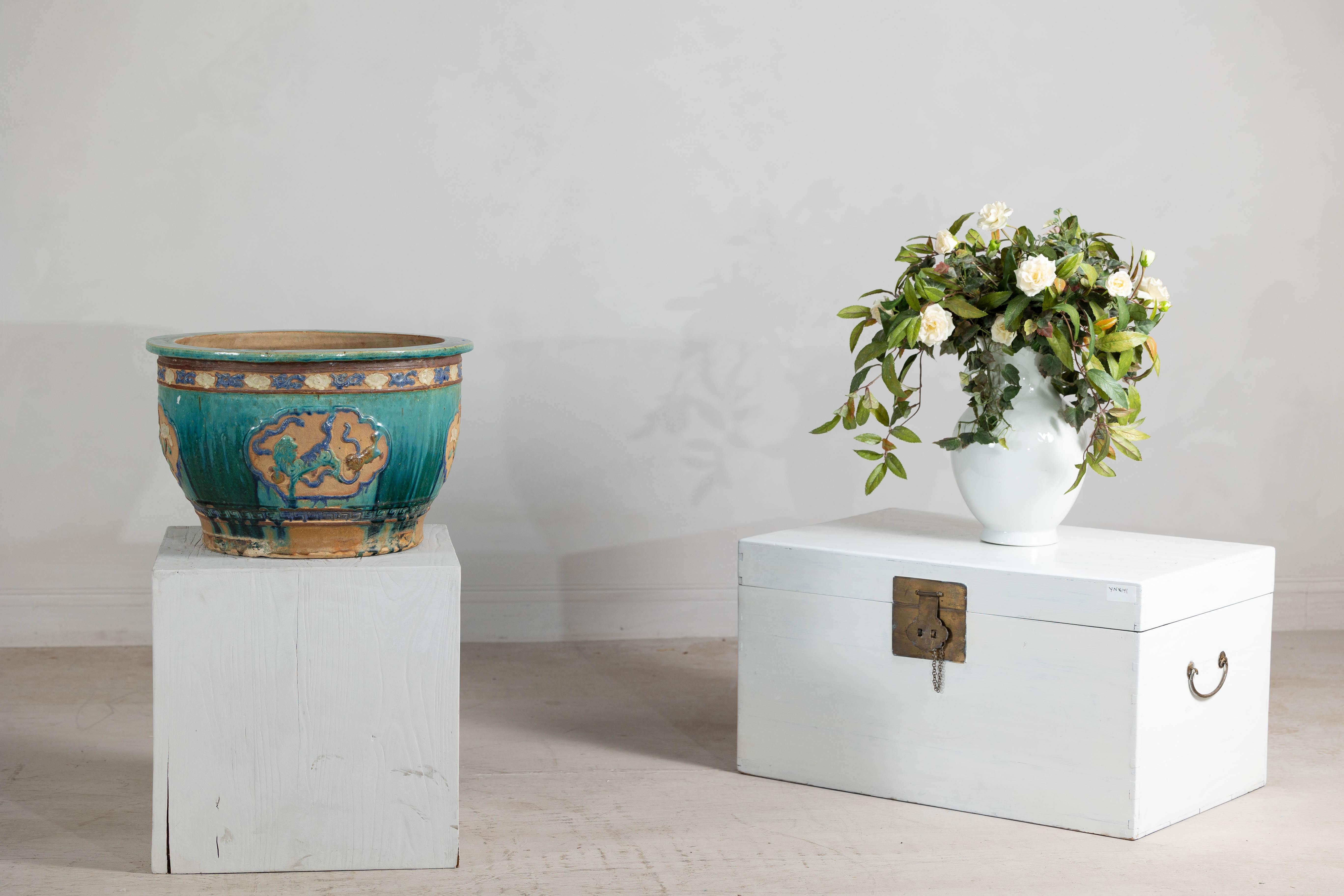 Cette ancienne jardinière annamite, avec sa glaçure turquoise frappante et ses motifs en relief complexes appliqués à la main, apporte à votre maison un morceau du riche patrimoine céramique du Viêt Nam. Sa forme arrondie est gracieusement ornée de
