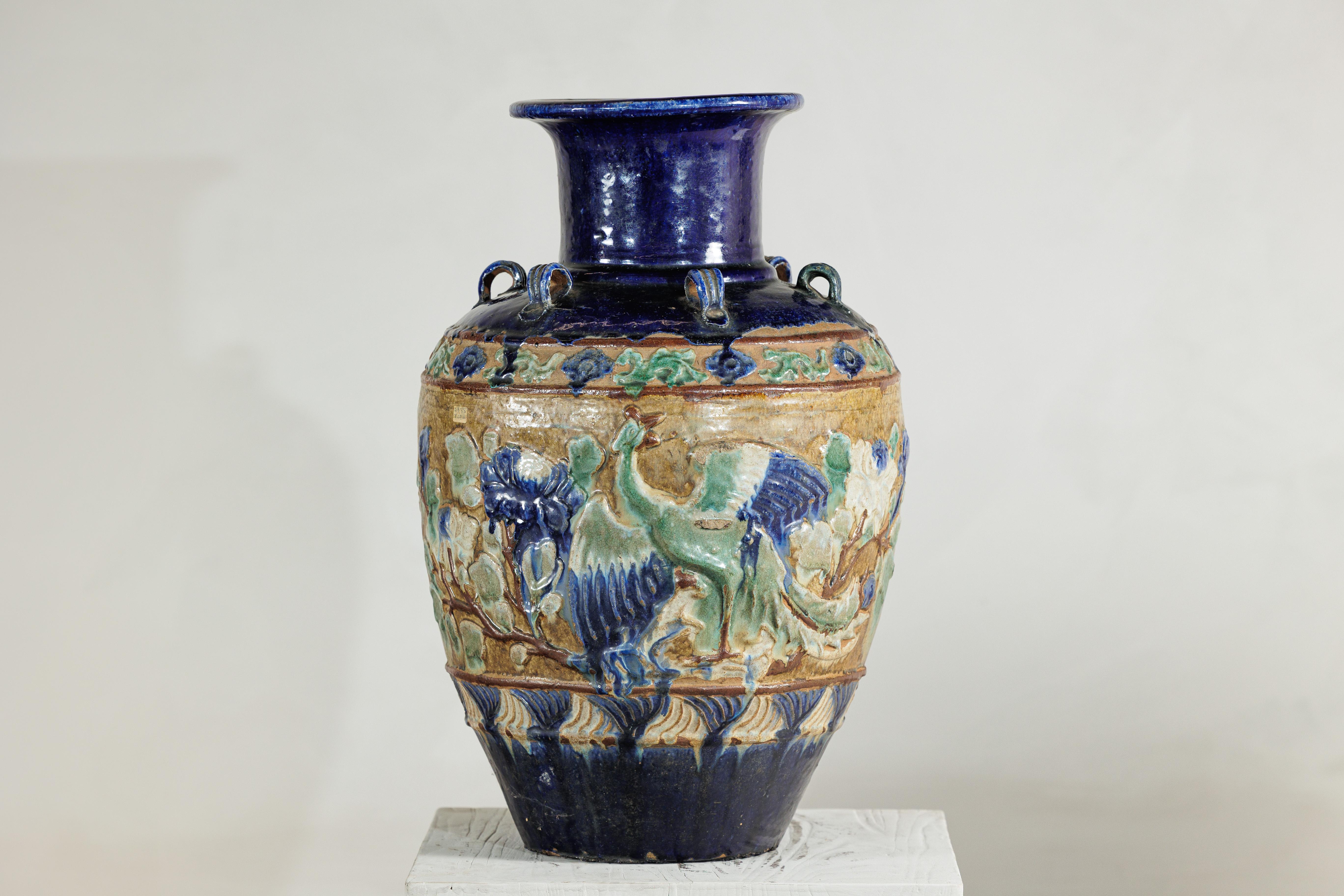 Esta impresionante jarra de agua anamita antigua, procedente de Vietnam, presenta un cuerpo ricamente modelado con decoración en relieve que representa fénix entre ramas en flor. El diseño está animado con una paleta de esmaltes azul cobalto, verde