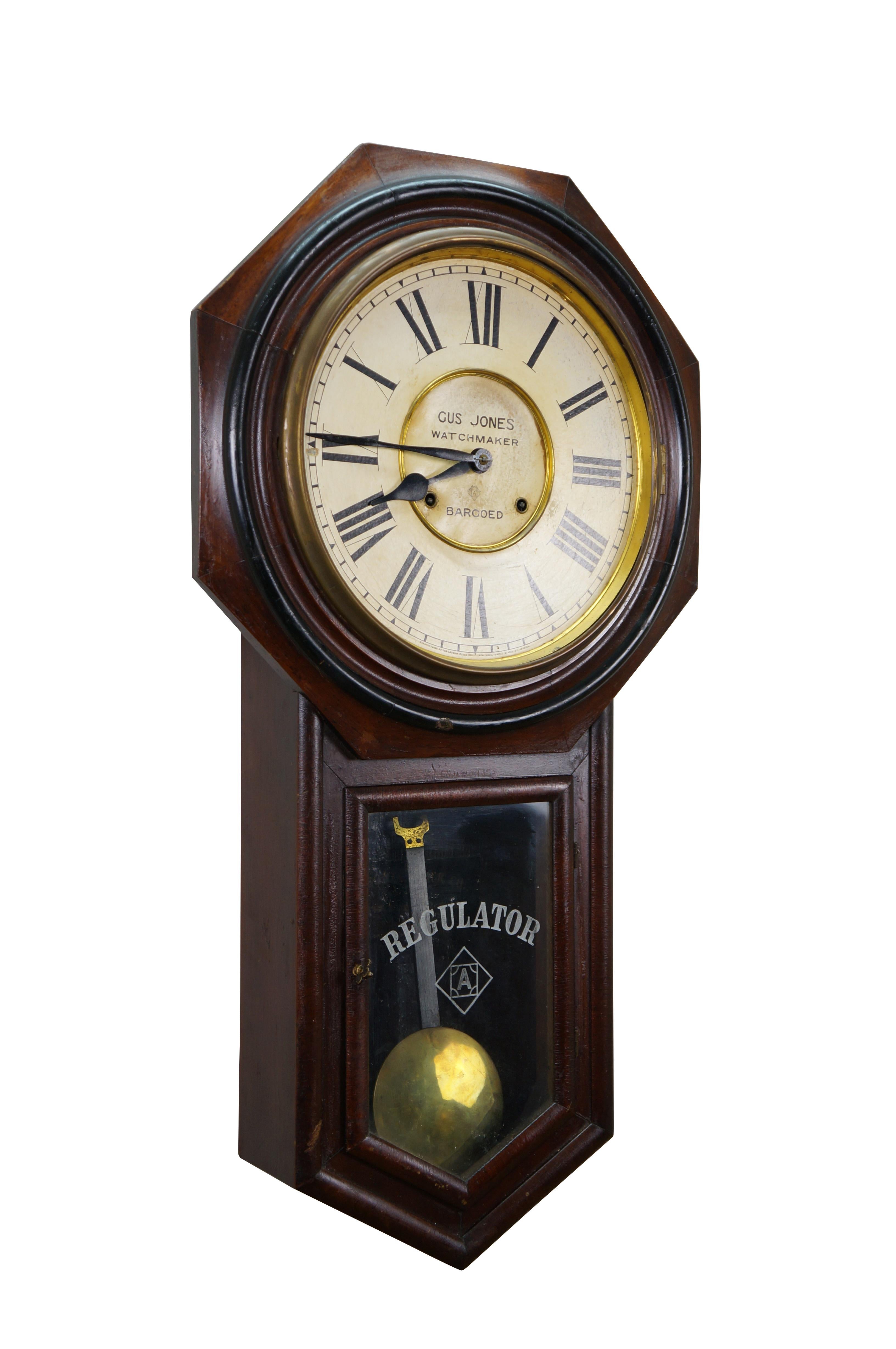 Early 20th century Ansonia Regulator key wound, chiming wall clock. Schoolhouse style mahogany case with glass door over round brass pendulum. White face with black Roman numerals and black metal hands. Center of face features an advertisement for