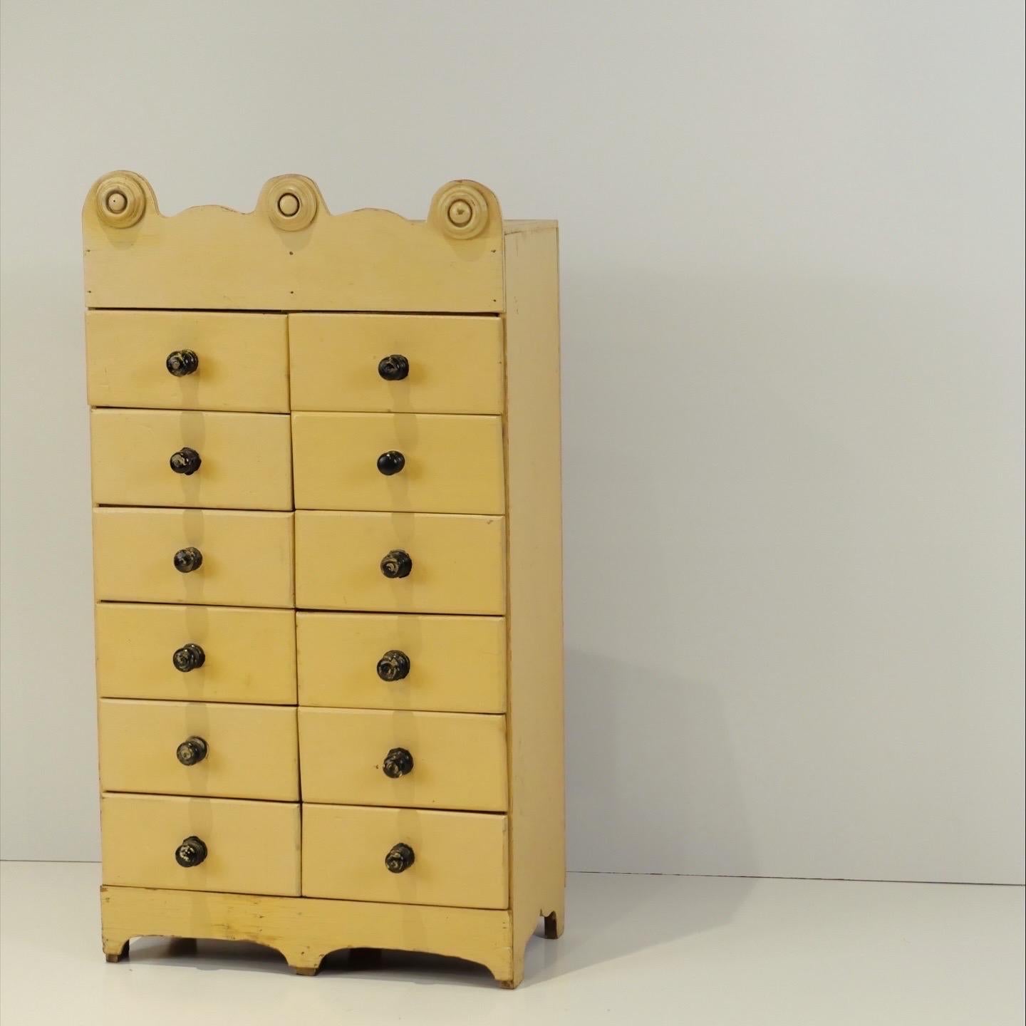Une charmante commode d'apothicaire à dix tiroirs, construite en planches de sapin de Douglas et peinte d'un jaune doux comme du beurre. Détail tourné le long du bord supérieur et riche en caractère. Patine d'usage, boutons en bois peints en noir.