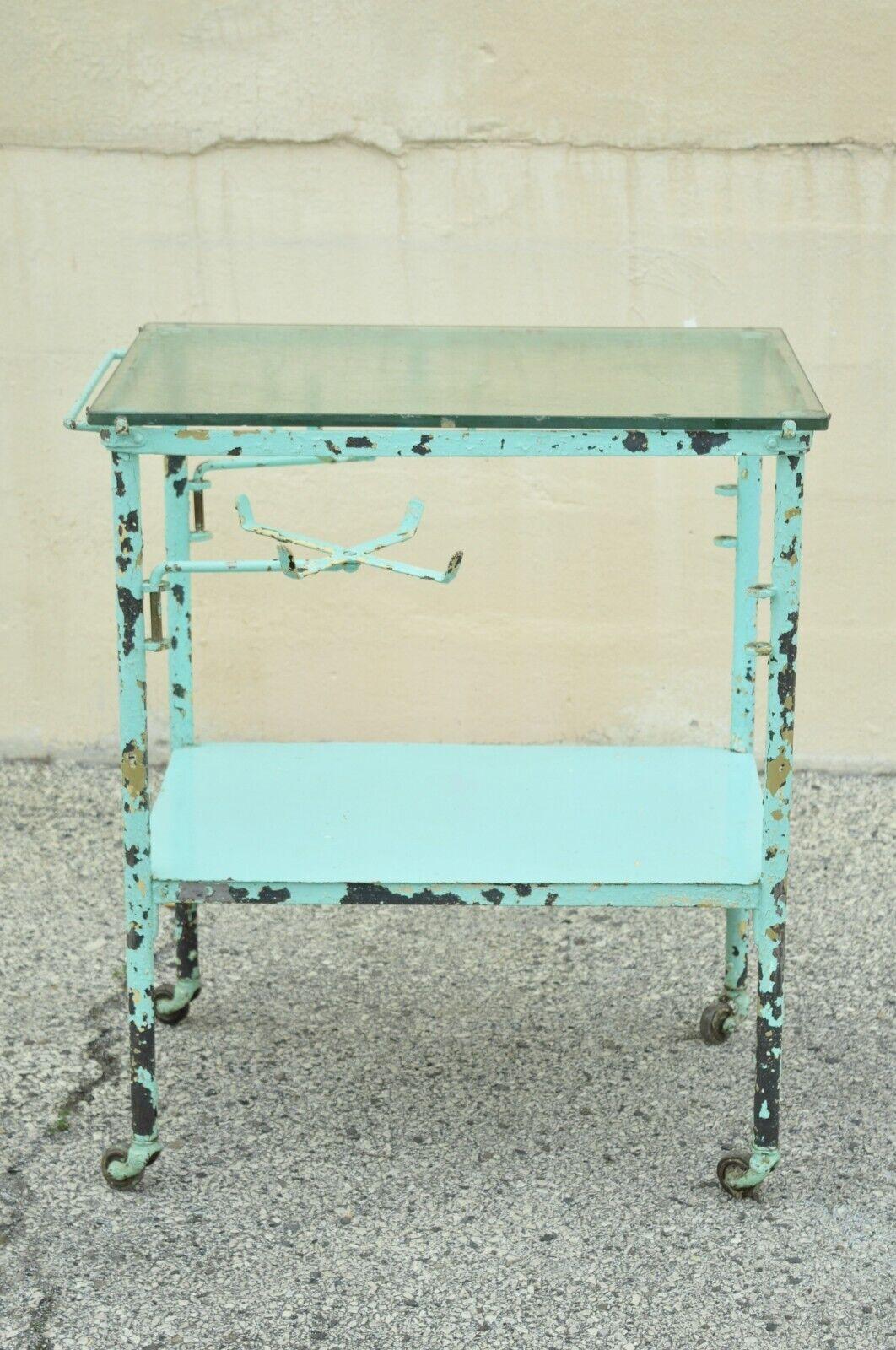 Antique aqua blue distress paint metal glass 2 tier medical dental cart table.
Item features (2) swing out supply holders, glass top, lower shelf, rolling casters, distressed finished, very nice antique item, quality American craftsmanship, great