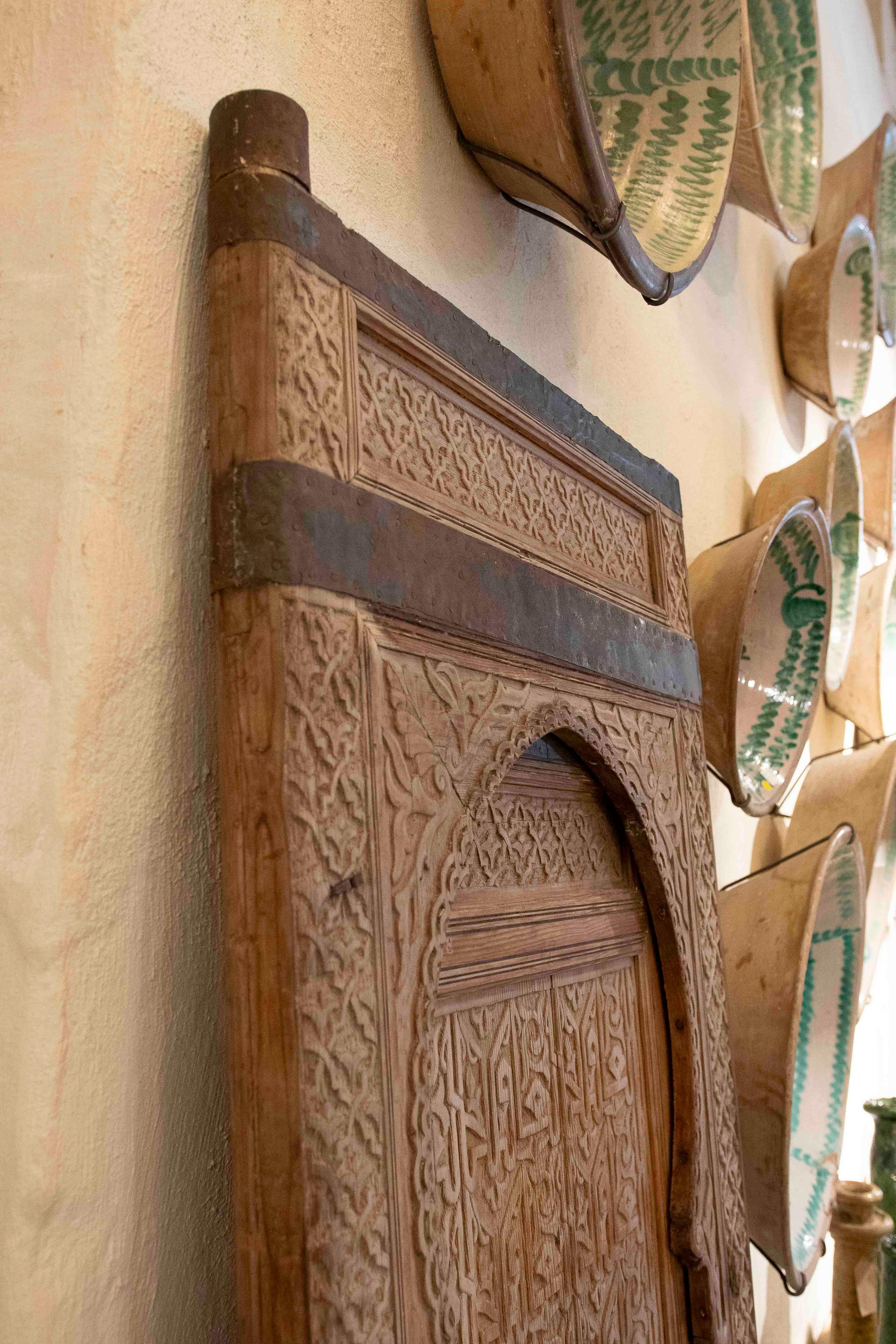 Prächtige antike maurische Tür aus handgeschnitztem Holz, verziert mit islamisch inspirierter Kalligraphie und geometrischen Motiven. Der imposante Hufeisenbogen und die kunstvollen Reliefs zeugen von der meisterhaften Handwerkskunst, die für die
