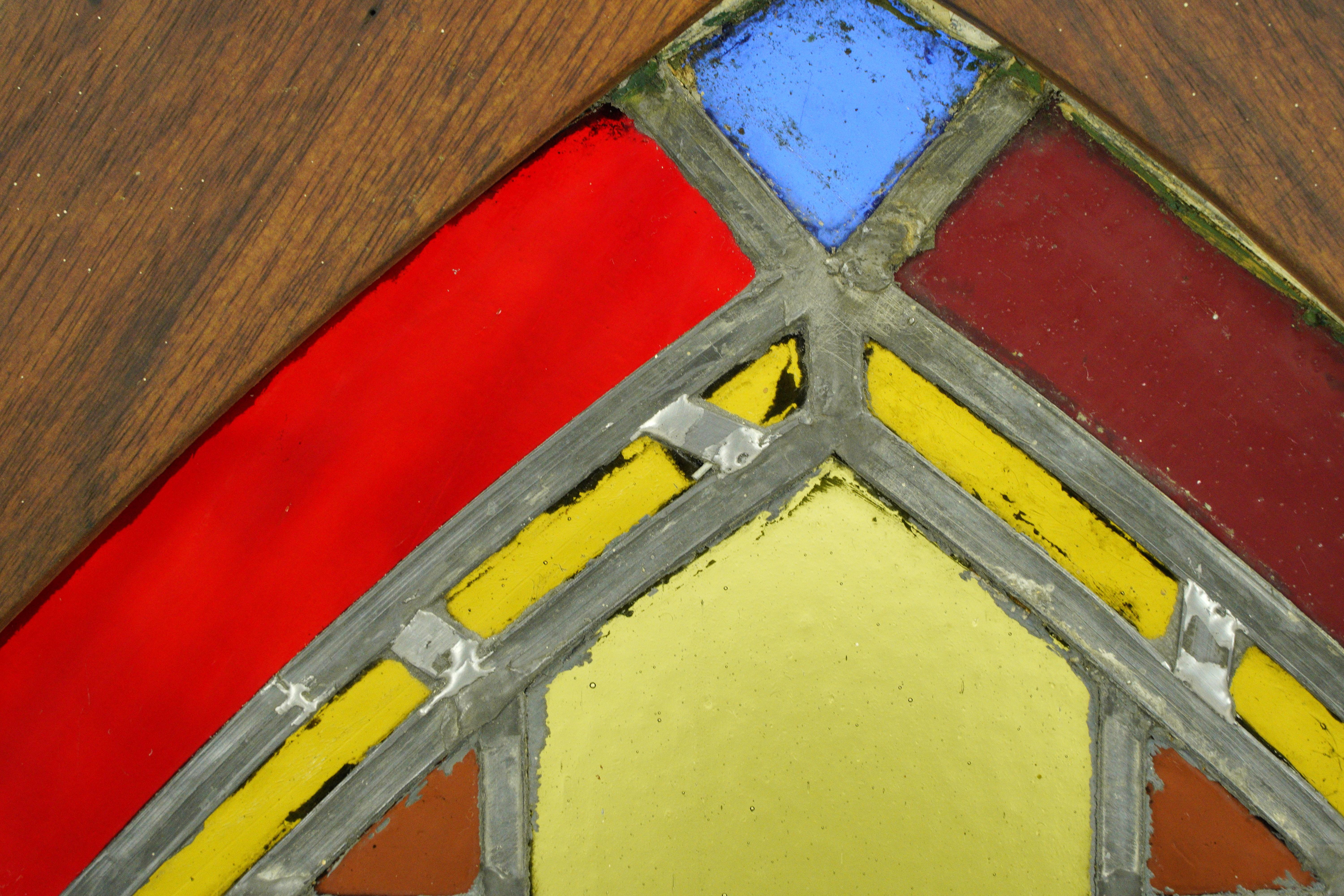 Antica finestra in legno di pino con cornice in vetro colorato piombato a forma di arco con una combinazione di colori primari. Buone condizioni, con lievi tracce di vernice superficiale e un foro di ritaglio dovuto al montaggio sul telaio. Uno