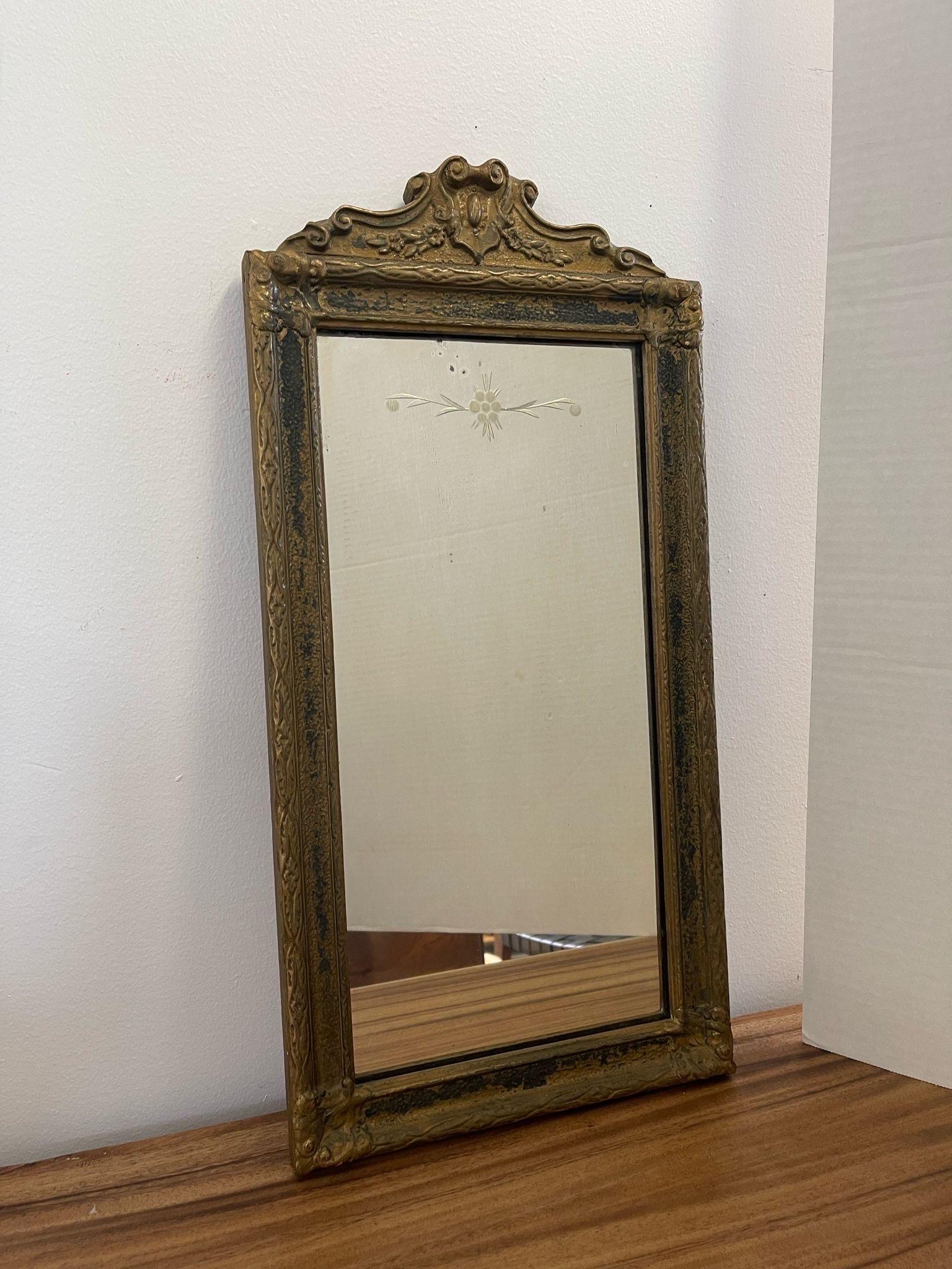 The Petina on the frame shows that it may have originally been gilted wood. Ornate detailing on the wooden frame with arched Top. Beautiful Petina and Aging to the frame and mirror. Possibly Circa 1920s. No Maker’s mark. Vintage Condition Consistent