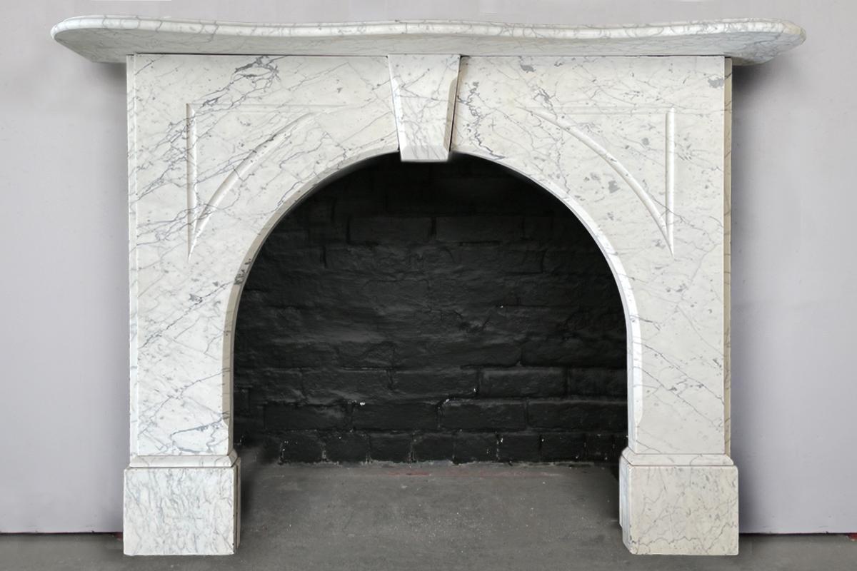 An arched Victorian fireplace surround of good proportions in well-figured pencil vain Carrara marble. The serpentine mantle with an ogee moulded edge sits above the arched jambs with flutes to the spandrels. A simple keystone tops the arch. Circa