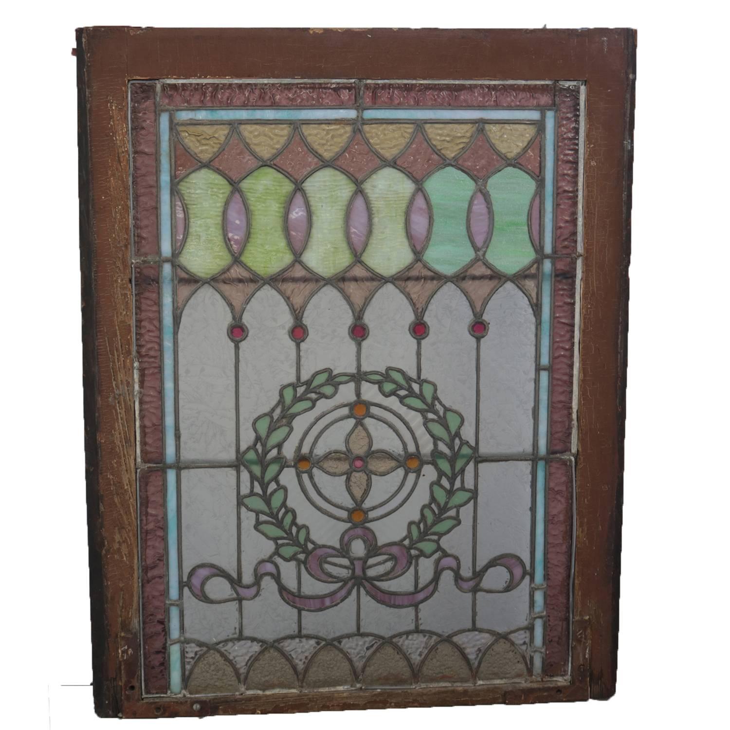 Antique architectural framed leaded mosaic stained and jewelled glass window features laurel wreath with stylized central flower and bow, circa 1880.

Measures: 31.5