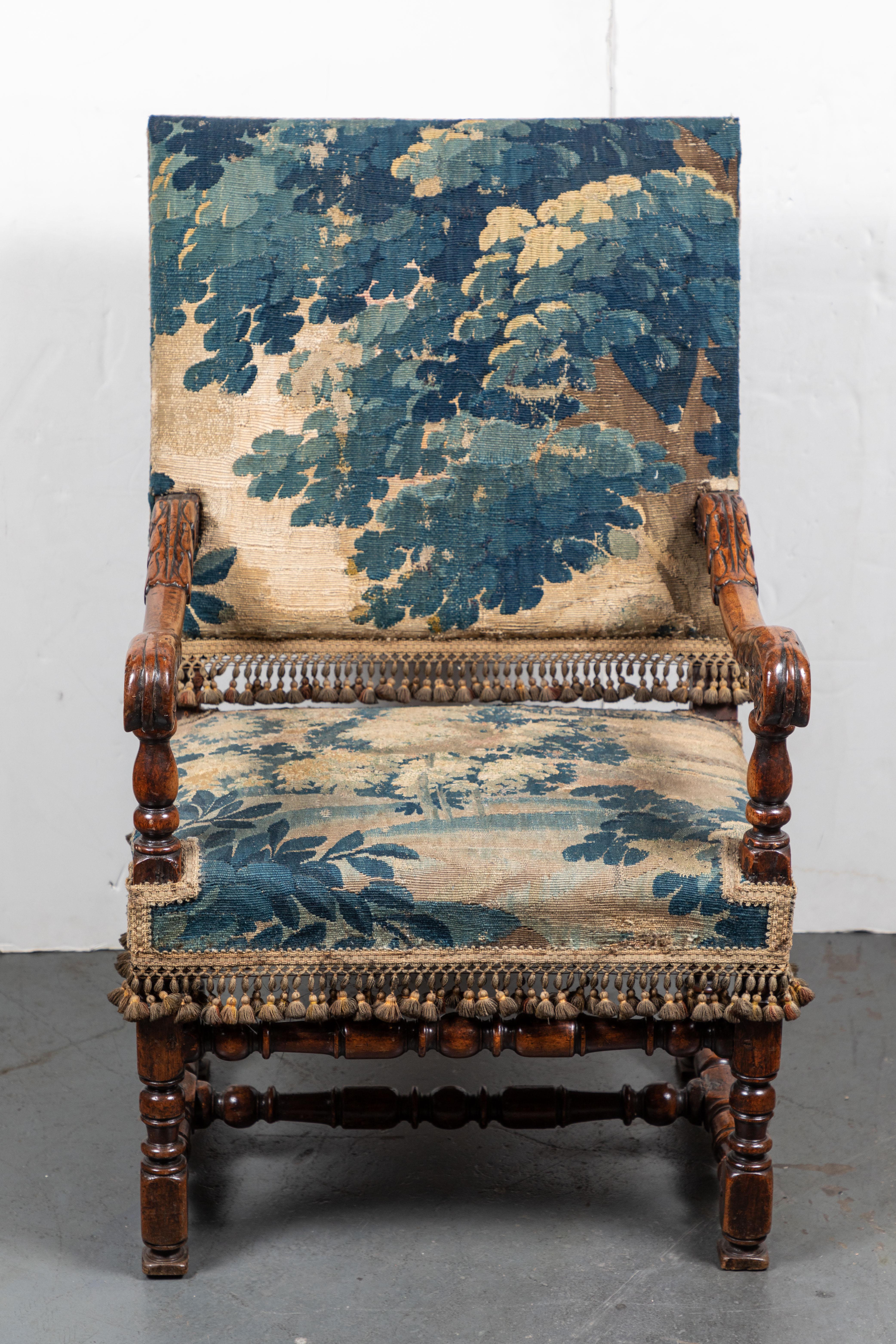 Absolutely lovely, French, 19th century, hand carved chair with scrolling arms terminating whirled, foliate hand-rests. The framed covered in an 18th century. Dutch tapestry, and embellished with period tassels.
