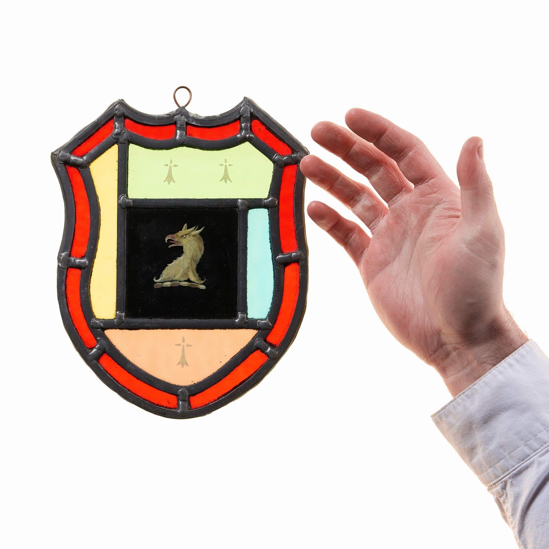 An antique stained glass armorial shield hanging panel dating to circa 1900.

Incorporating both heraldic and Victorian styles, the crest depicts a handpainted, detailed head of an eagle a black background and bold red border.

Hang in a window or
