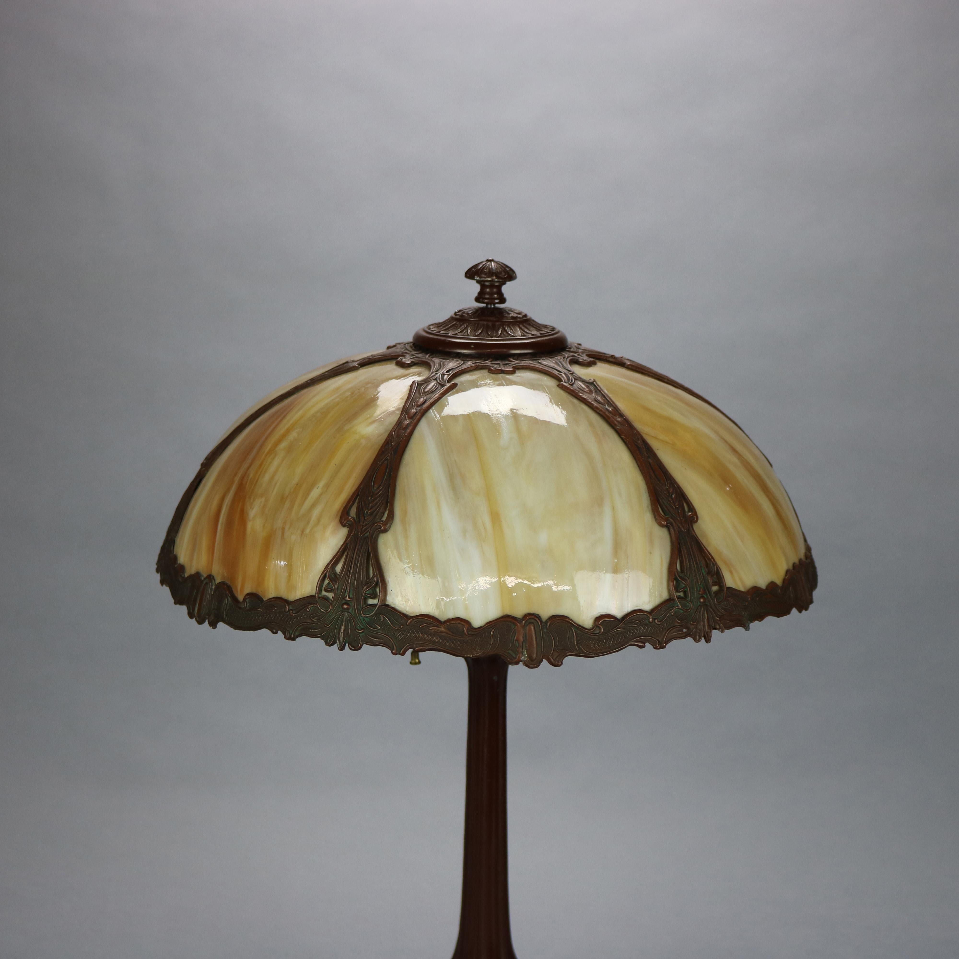 An antique Art and Crafts table lamp in the manner of Bradly and Hubbard offers dome shad housing bent slag glass over cast double socket base, c1910.

Measures: 23
