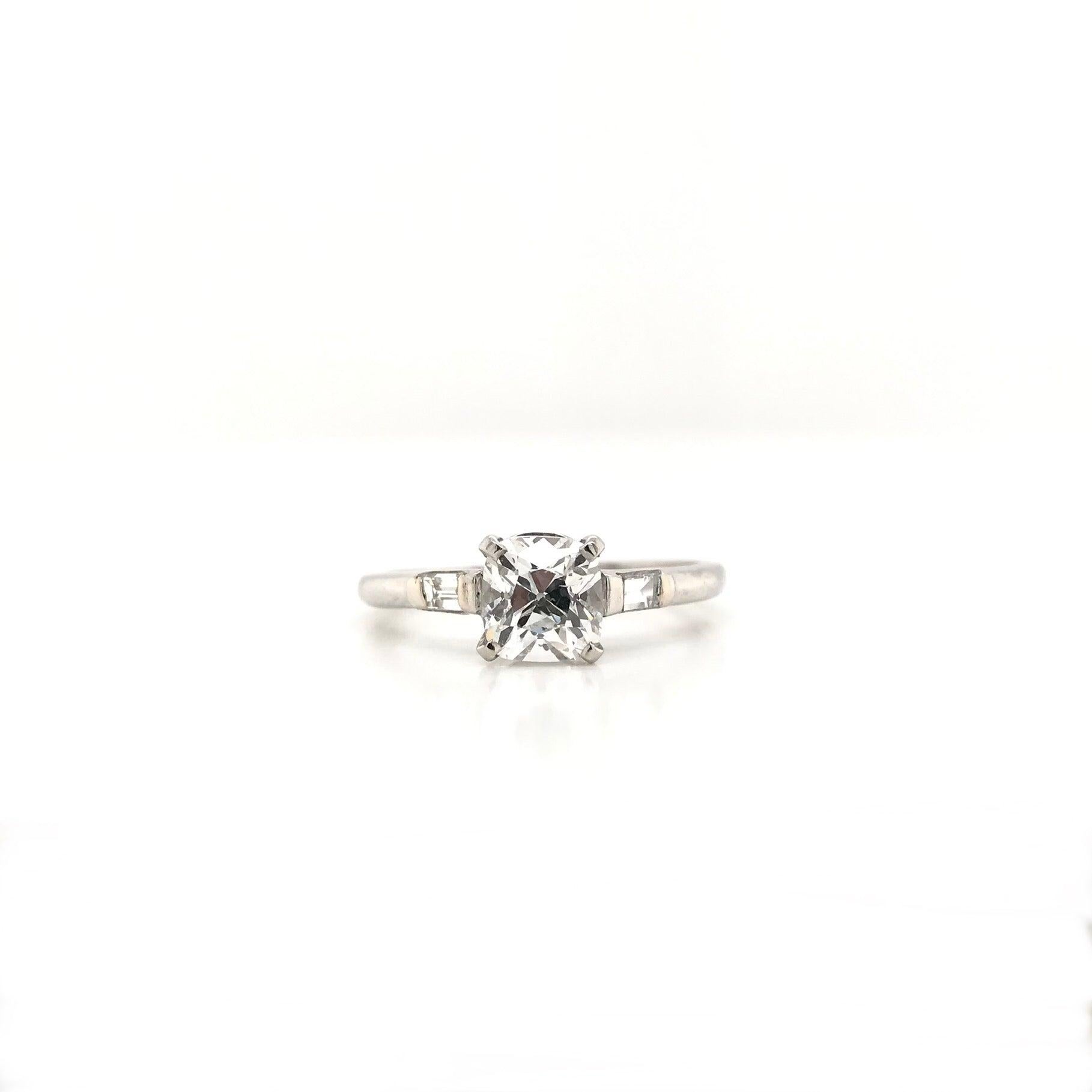 This beautiful antique piece was handcrafted sometime during the Art Deco design period (1920-1940). The platinum setting is a classically simple solitaire style with two baguette cut diamond accents. The center diamond is an Old Mine cut measuring