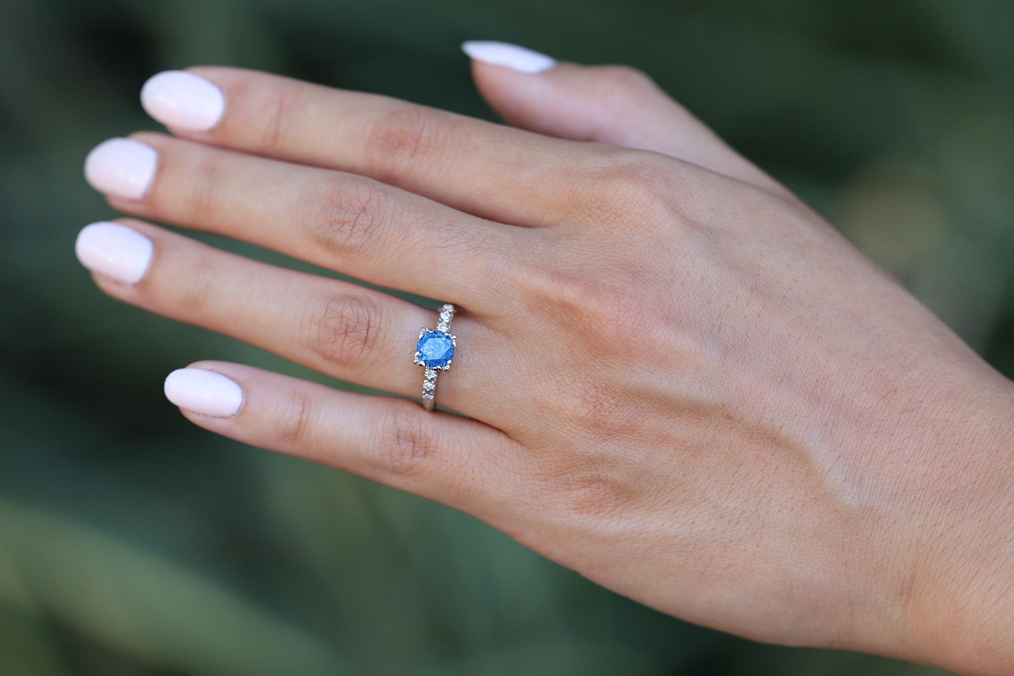 An authentic antique, this affordable sapphire engagement ring was skillfully handcrafted during the 1920s Art Deco era. This lovely heirloom features a velvety-blue sapphire solitaire weighing 1 carat, perched in an enduring platinum setting. The