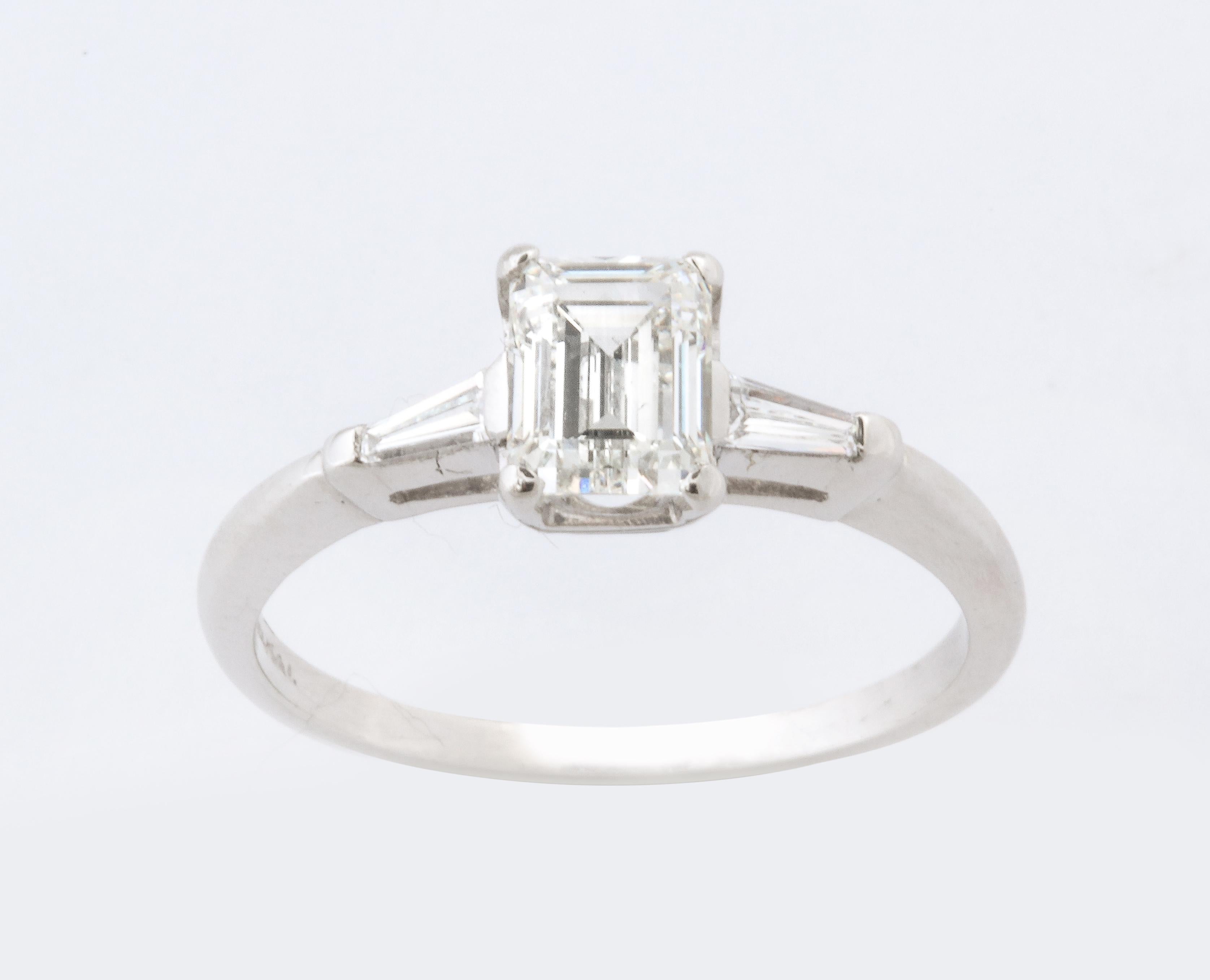 A stunning Emerald Cut  fine quality diamond set in a classic platinum mounting with baguette cuts on each side typical of the 1920/1930
The center diamond is  1.07 CT’s vs1 G color.  A lovely classic ring.