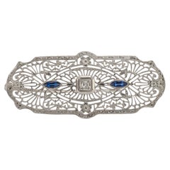 Antiguo broche Art Decó de oro blanco de 10 quilates con diamantes y zafiros filigranados