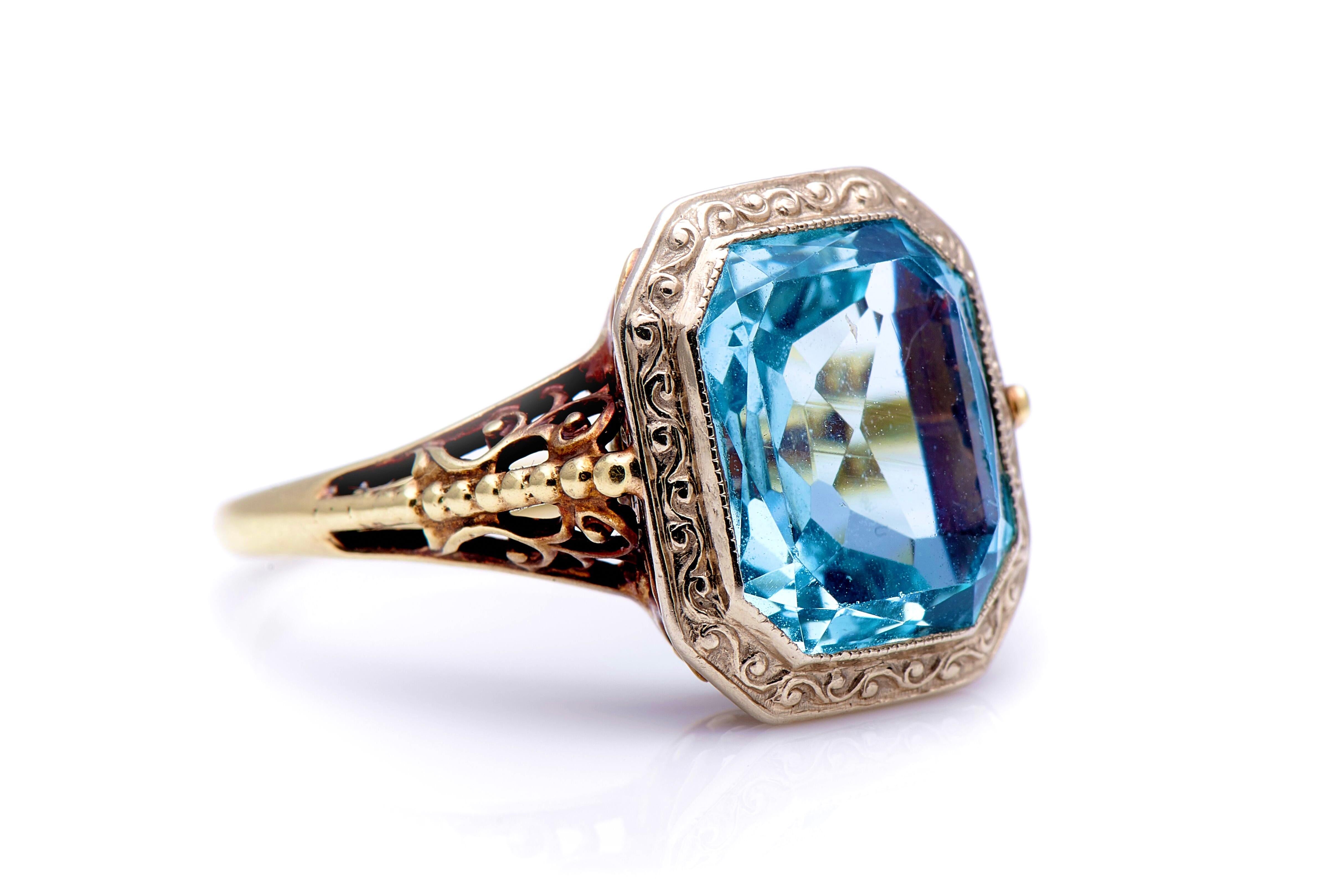 Aquamarine ring, early 20th century. The simple, geometric cut of this aquamarine is juxtaposed with an elaborate decorated mount, with millegrained borders, chased scrollwork around the setting and an intricately pierced gallery. The pale blue form