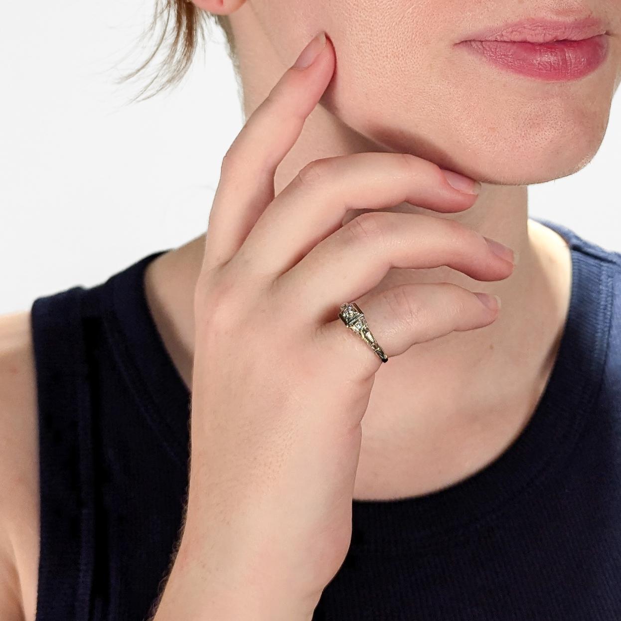 Bague de fiançailles Arte Antiques Fine Arts.

En or blanc 14 carats.

Serti avec un diamant blanc de taille ronde d'environ 3,4 mm de diamètre et deux diamants d'accentuation plus petits dans une monture filigrane ornée.

Marqué 18K sur la