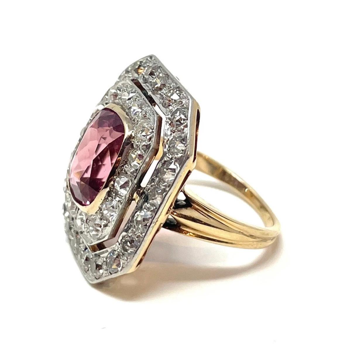 A classic Art Deco cocktail ring in 14K gold and platinum containing a vivid pink tourmaline surrounded by two rows of sparkling old European cut diamonds.

The pink tourmaline is approximately 5.20 carats and the surrounding old European cut