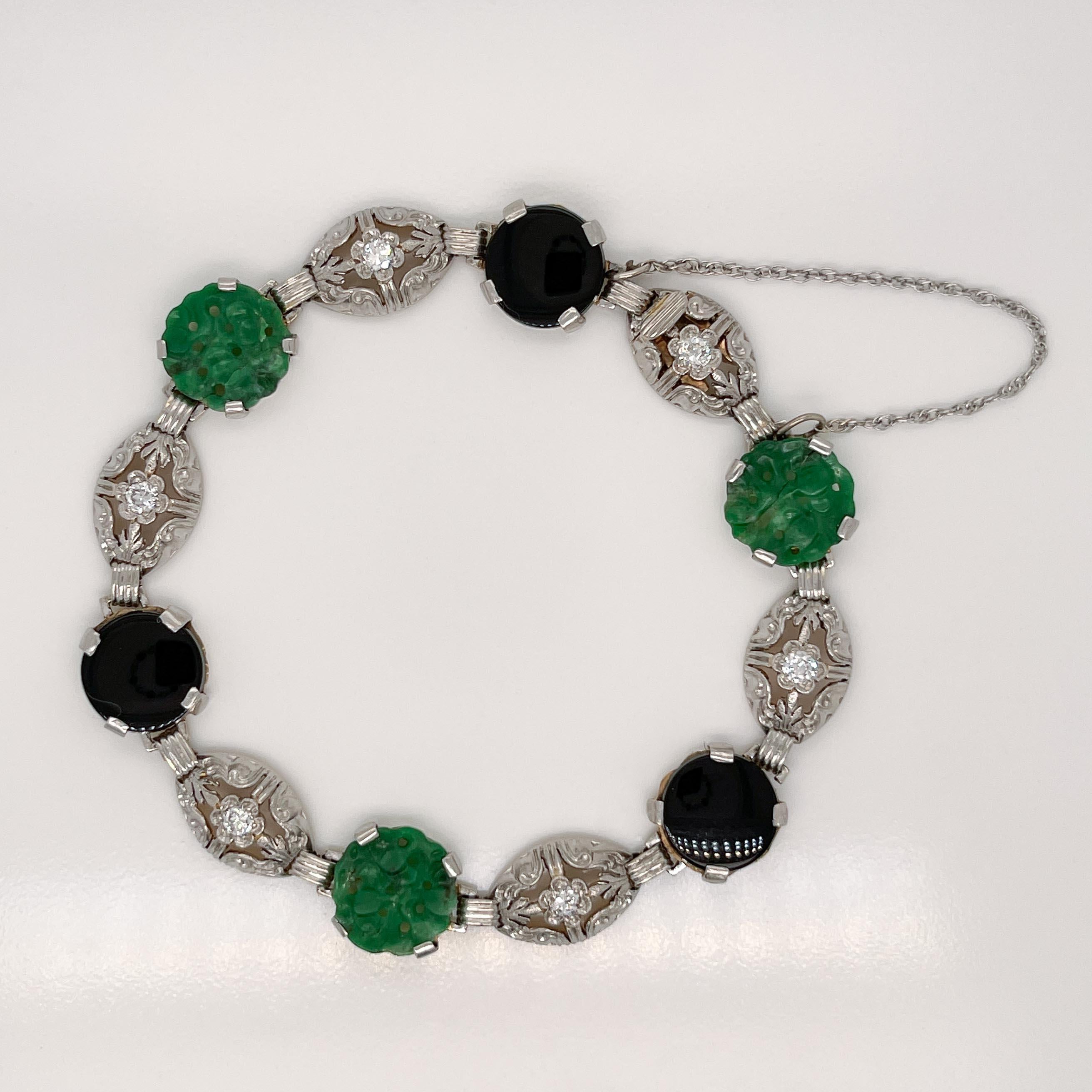 A very fine Art Deco period bracelet. 

In 14k white gold. 

With alternating links set with carved green jade cabochons and smooth, round black onyx cabochons.

Links with round white diamonds in a stylized floral design offset each cabochon links.