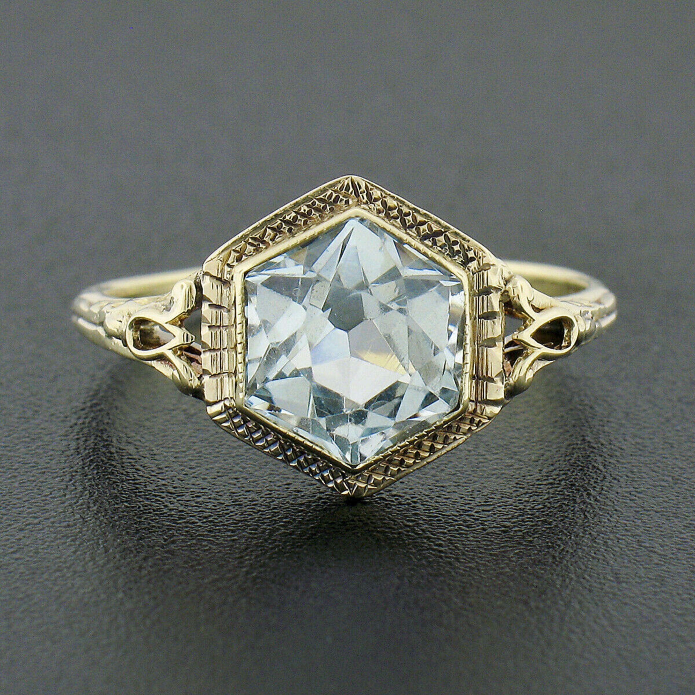 This is an absolutely gorgeous antique ring that was crafted in solid 14k yellow gold during the art deco period. It features a stunning custom hexagon cut aquamarine solitaire that is neatly bezel set at the center, showing a beautiful transparent